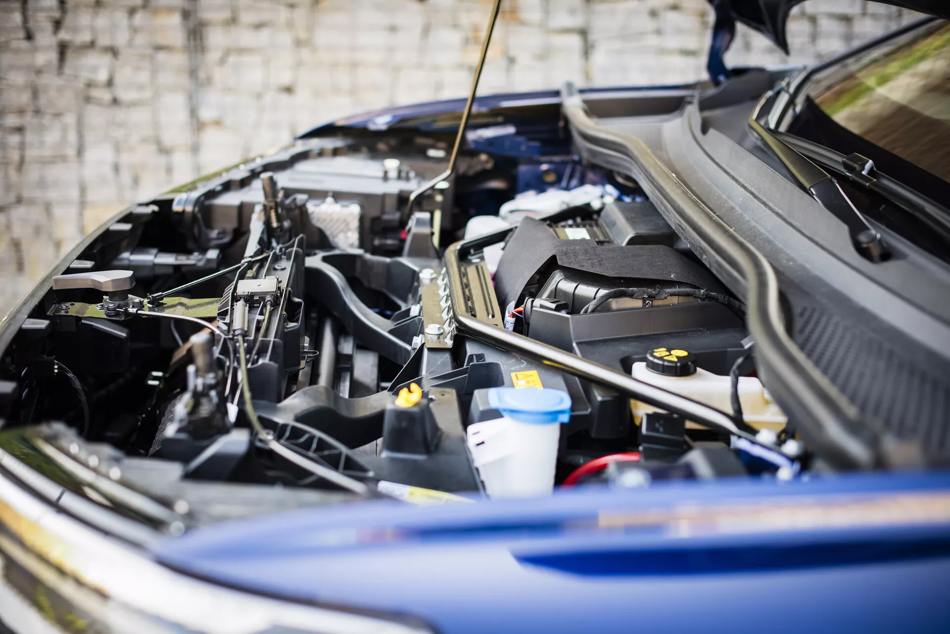 Nagy felbontású kép egy 2021-es Audi Q4 e-tron nyitott motorháztetőjéről, amely bemutatja a belső alkatrészek elrendezését és tervezését, beleértve a motor felső burkolatát, a folyadéktartályokat és az akkumulátorpólusokat, az autóipari mérnöki munka és technológia fókuszálva.