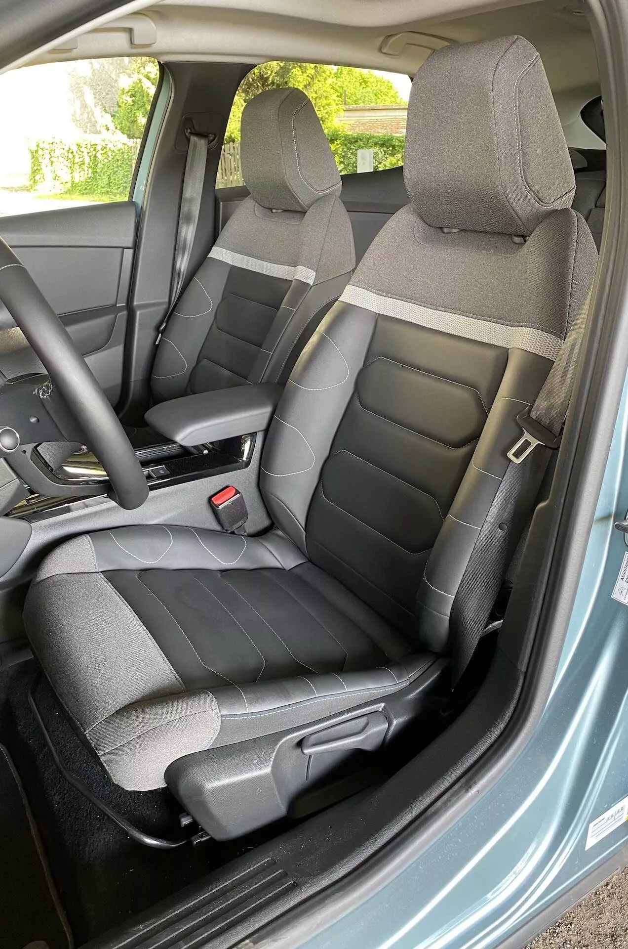 Citroen C4 2020 (e-C4) belső nézete, a vezetőoldalra koncentrálva, nyitott ajtóból szögben készült felvétel, amelyen látható a kormánykerék, az ülések és a műszerfal egy része a kormánykeréken lévő vezérlőkkel.