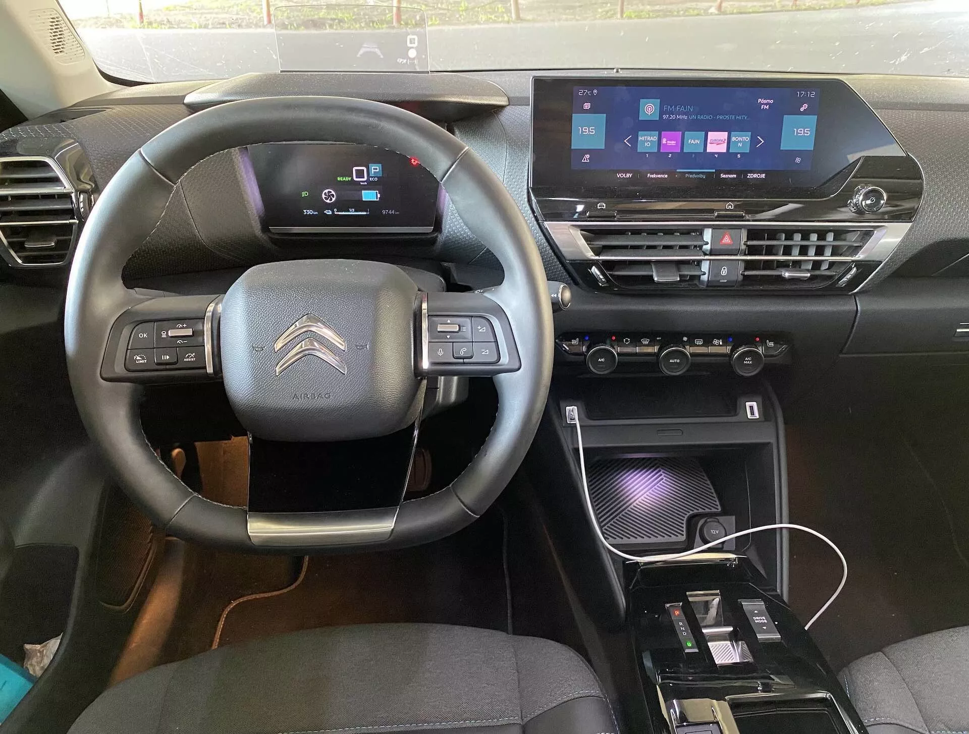 A 2020-as Citroën C4 (e-C4) belső nézete a vezető üléséből, háromküllős kormánykerékkel, beépített vezérlőkkel, digitális műszerfallal és modern középkonzollal érintőképernyős infotainment rendszerrel, klímavezérlőkkel és töltőhellyel.