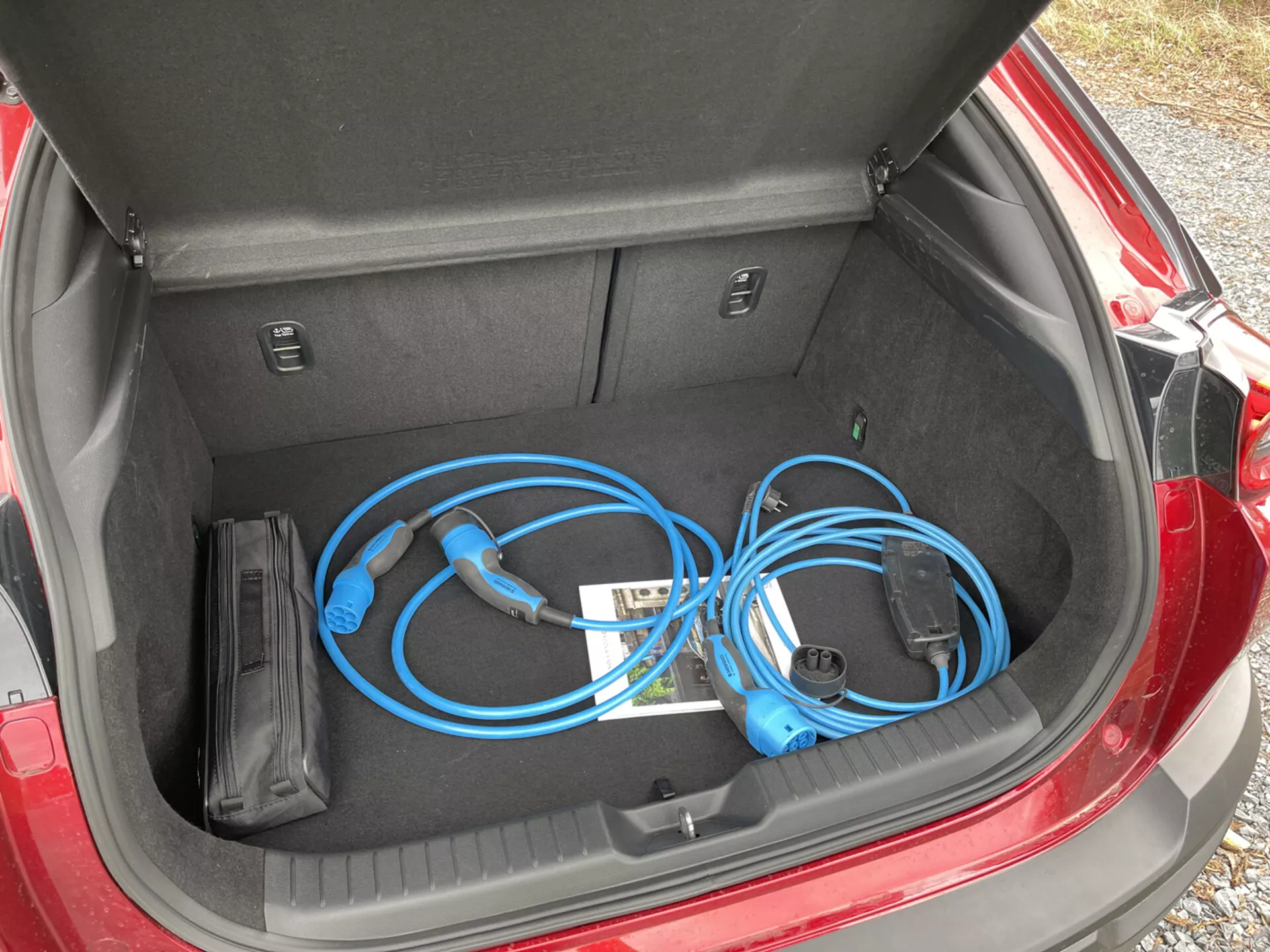 2020-as Mazda MX-30 nyitott csomagtartója, amely egy hordozható elektromos jármű töltőkábelt mutat be közelről, felülnézetből balról, bemutatva a tiszta és lapos tárolóteret az belső rekeszekkel együtt.