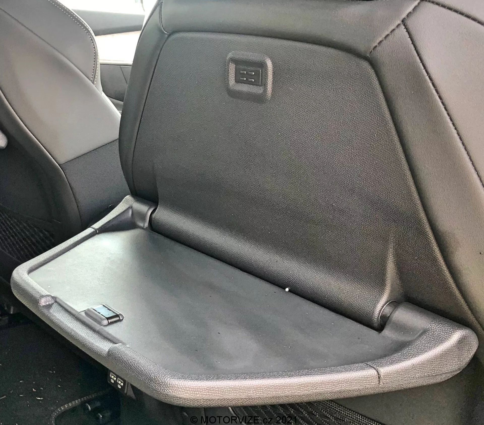 Peugeot 5008 2021 belső nézete hátsó üléssel, amely kihajtható kartámaszt vagy asztalkát tartalmaz, kárpitozása szövet és bőr keverékével, valamint egy integrált képernyővel vagy vezérlőpanellel az első utasülés fejtámlájának hátulján.