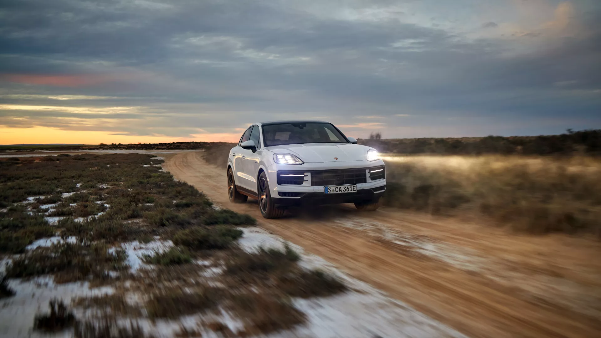 2023-as Porsche Cayenne 9YA Facelift modell terepen vezetve, bemutatva az előlapon háromnegyedes nézetben, LED fényszórókkal, aktív felfüggesztéssel és összkerékhajtásos rendszerrel szürkületi beállításban