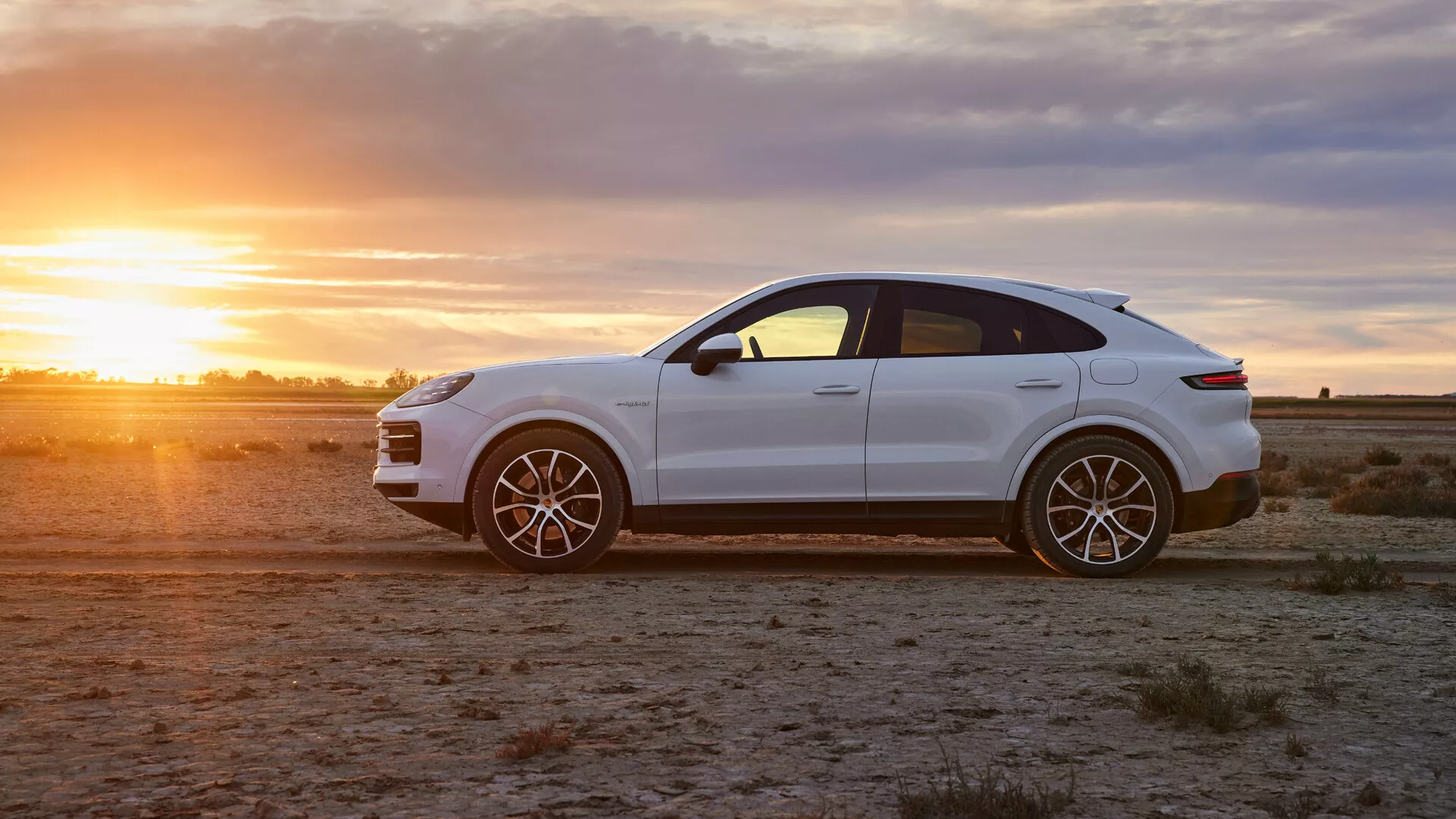 2023-as Porsche Cayenne luxus crossover SUV fényes fehérben száraz területen az aranyórában, oldalnézeti profillal, sportos ötvözött kerekekkel és elegáns tervezési jellemzőkkel