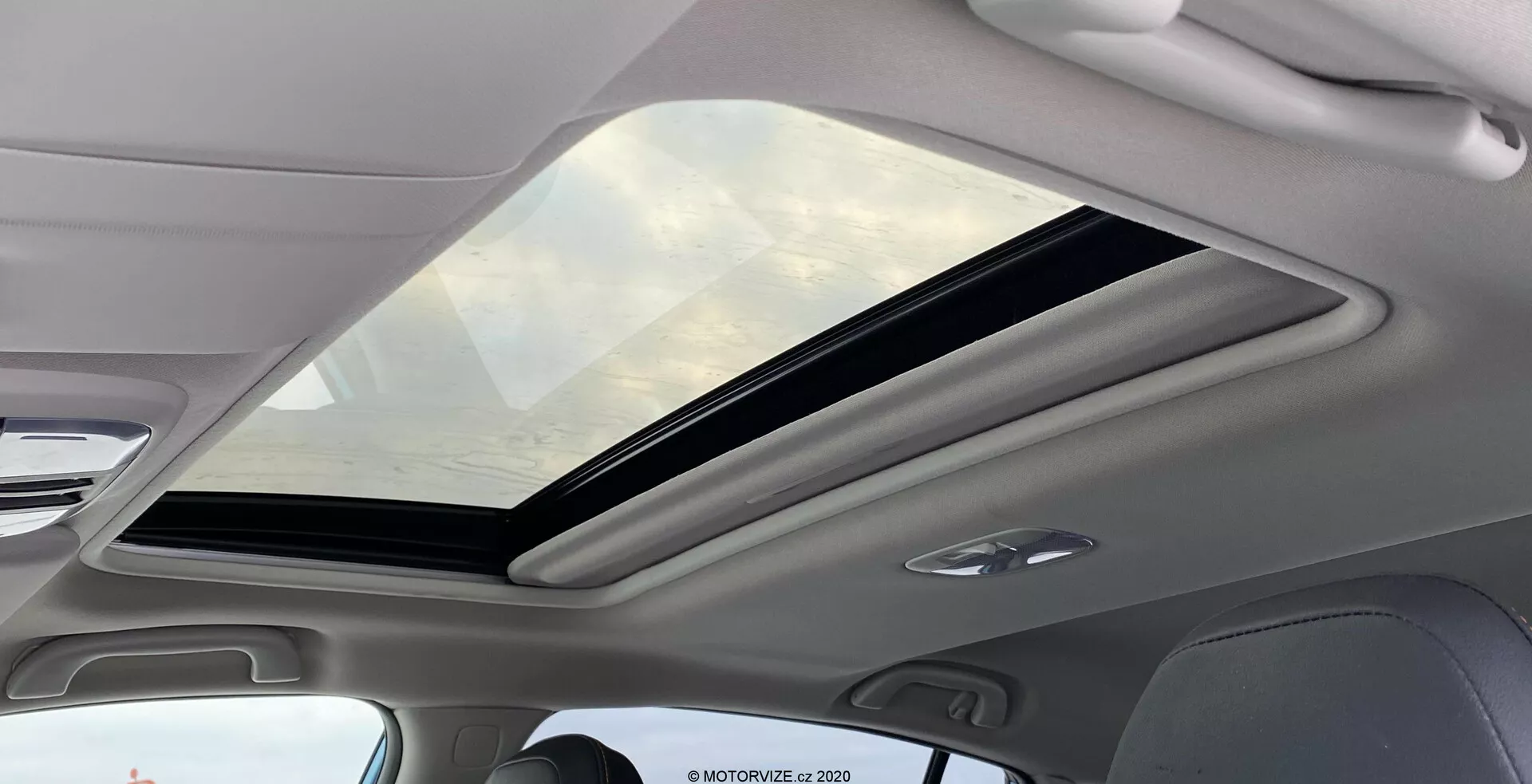 A Subaru XV 2018 1.6i Trend Lineartronic belső nézete a nagy panoráma napfénytetőre összpontosítva. A napfénytető az utastér elejétől a hátsó részéig terjed, részben nyitva csúszó mechanizmussal. A színezett üveg UV-védelmet biztosít, fokozva a belső tér tágasságának érzését. A napfénytetőt körülvevő belső burkolat világos színű, amely kiegészíti a modern esztétikát. A tetőburkolatba integrált LED kabinvilágítás látható, jelezve az energiahatékony, hosszú élettartamú megvilágítást.