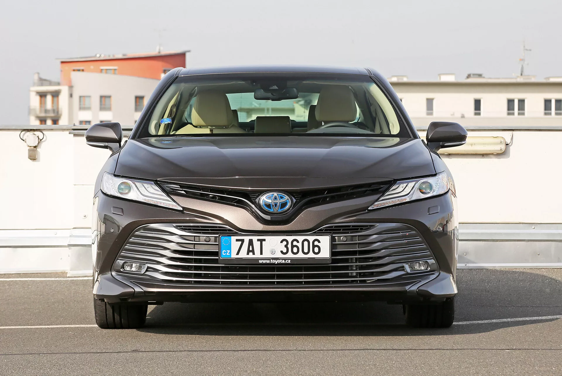 2001-es Toyota Camry Limousine első nézete, LED fényszórókkal, összetett hűtőrács-dizájnnal az aerodinamika és a hűtés érdekében, városi háttérrel és tiszta égbolttal