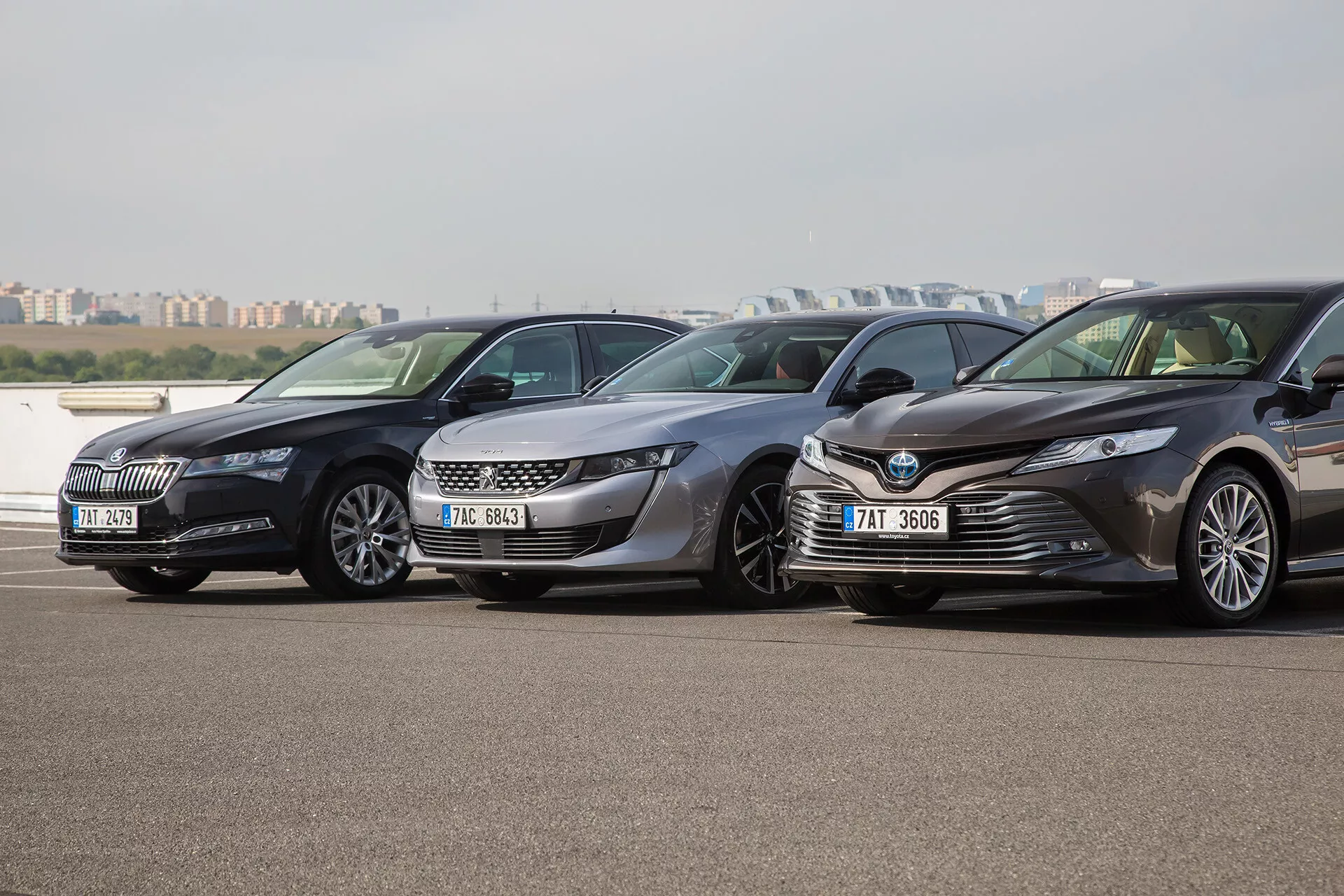 Három Toyota Camry limuzin, 2001-es modellév, egymás mellett parkolva egy kültéri parkolóban, balra nézve, tisztán látható a modern első hűtőrácsaik, fényszóróik és aerodinamikai terveik