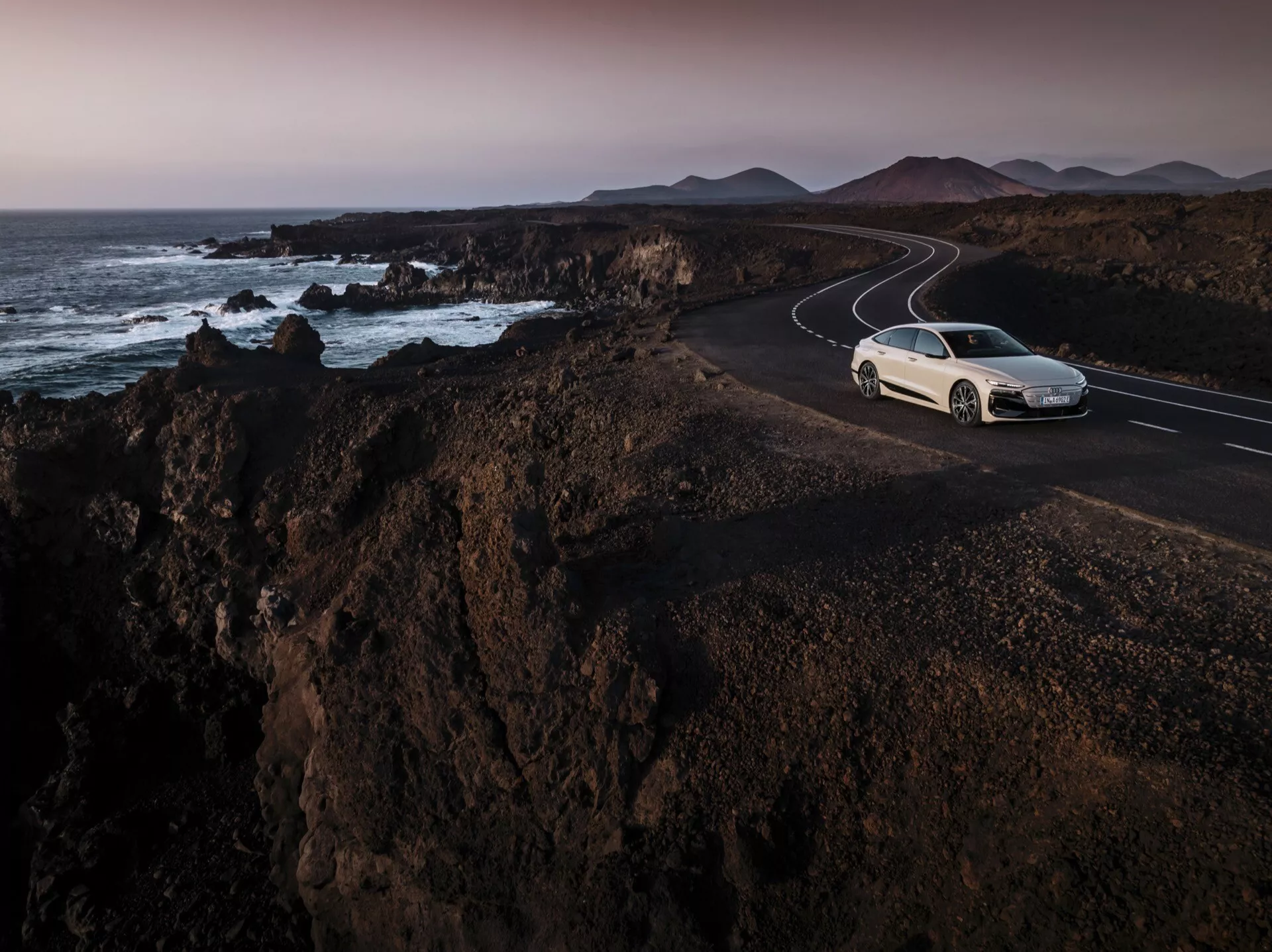 2024-es Audi A6 e-tron - Karcsú elektromos szedán modern aerodinamikával, élvonalbeli technológiával és futurisztikus dizájnnal. Gleccserfehér metál színben, jellegzetes LED fényszórókkal és áramvonalas profillal szerepel.