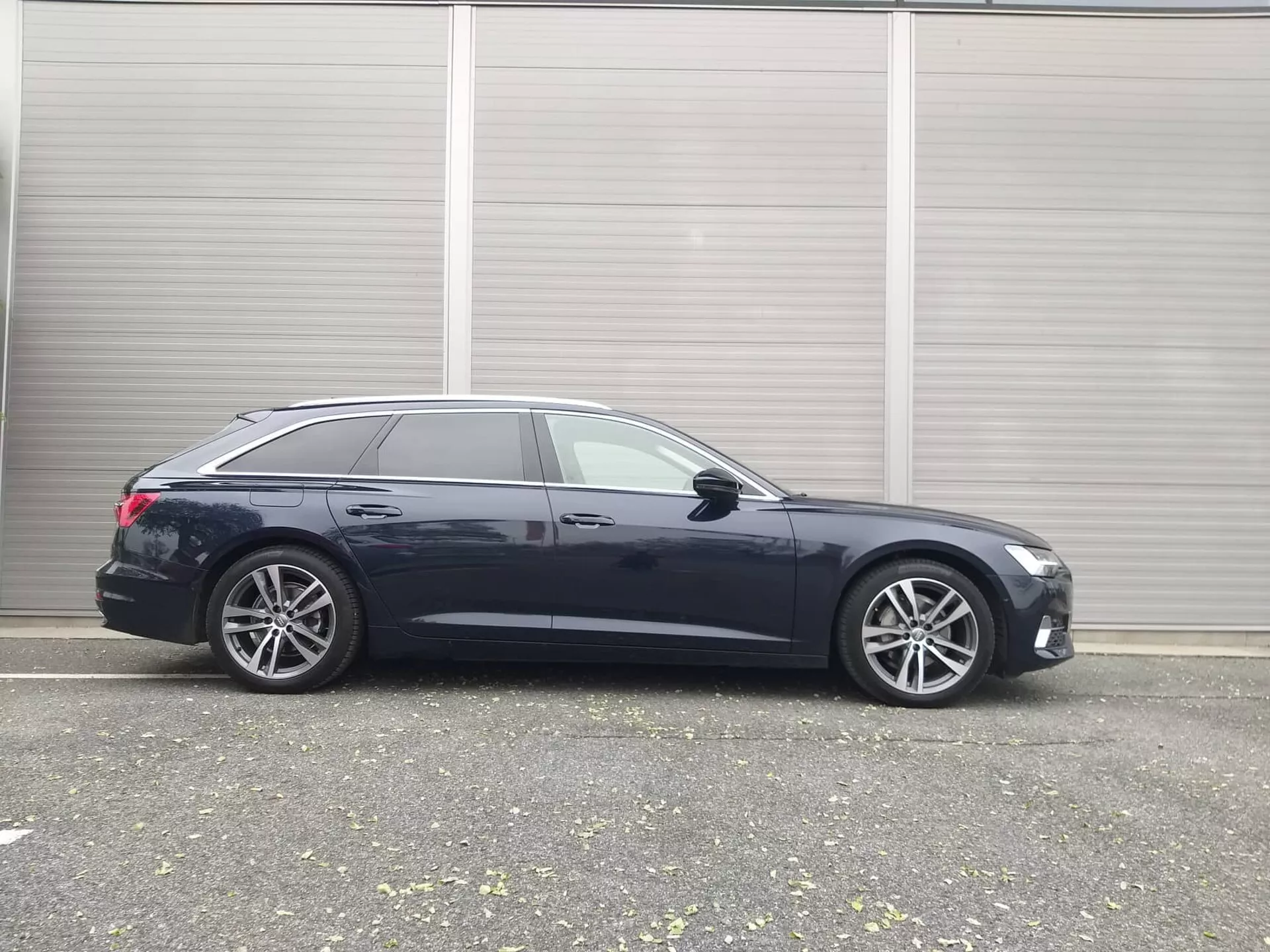 2018-as Audi A6 kombi oldalnézete, amely elegáns tervezést, fejlett technológiai jellemzőket és prémium ötvözetű kerekeket mutat, ipari környezetben parkolva