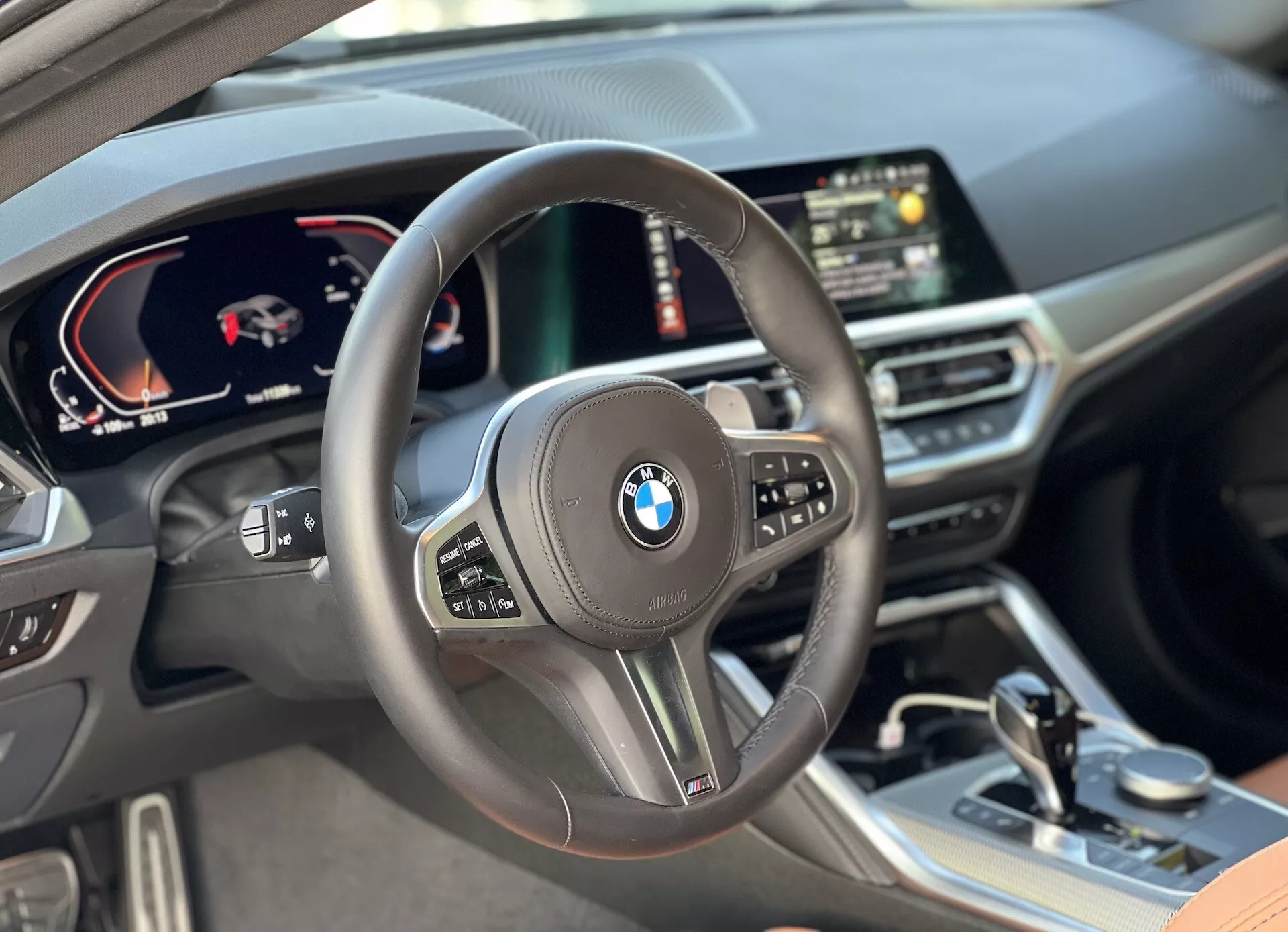 A 2022-es BMW 2-es sorozat kupé belső látványa vezetői perspektívából, középen elhelyezett, multifunkcionális gombokkal ellátott kormánykerékkel, digitális műszercsoporttal, amely sebességmérőt és fordulatszámmérőt mutat, központi digitális kijelzővel GPS navigációval és prémium anyagokkal, beleértve a bőr felületeket és gondosan tervezett díszítőelemeket a kabinban.