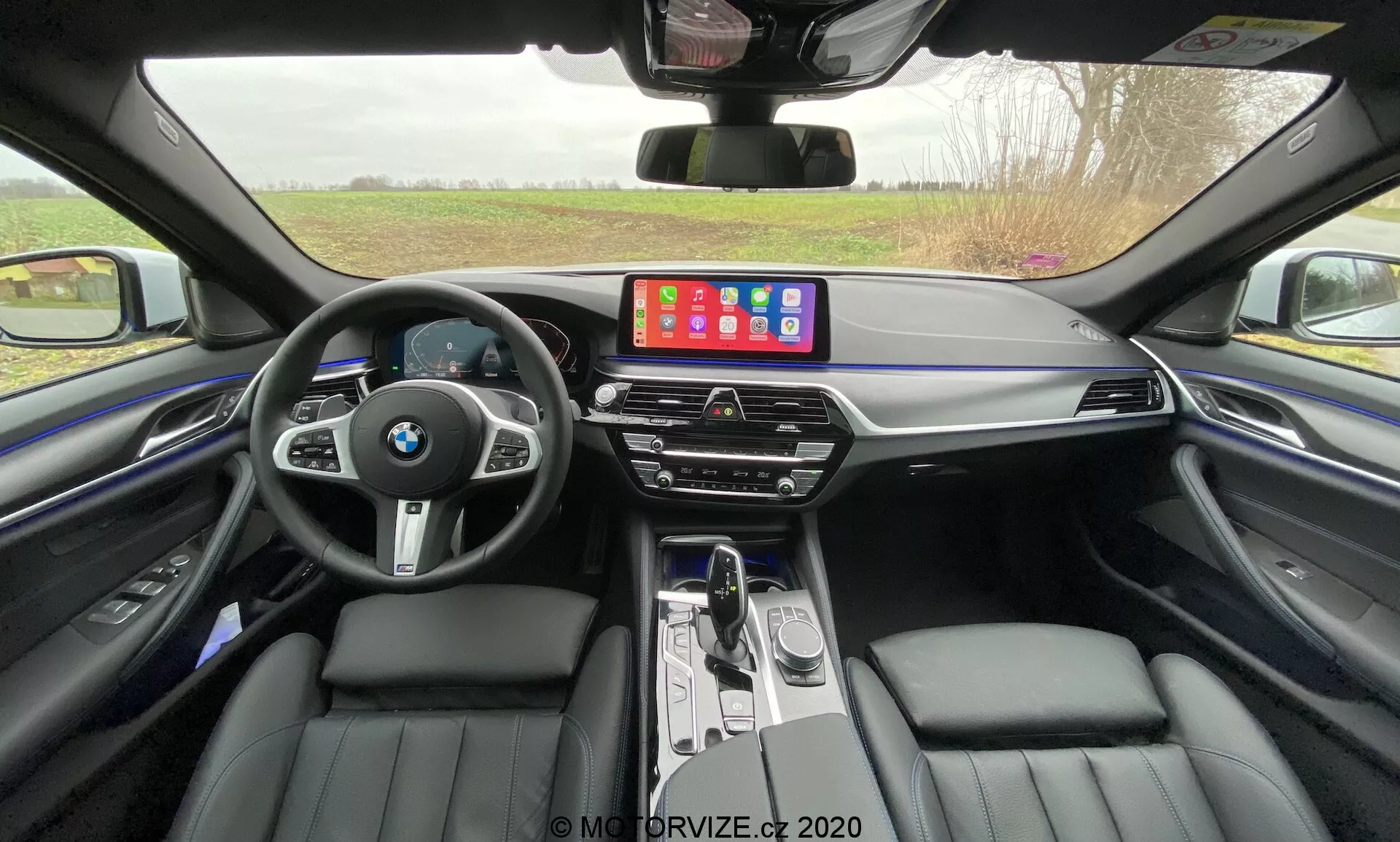 A 2020-as BMW 520i Touring Steptronic első nézete elegáns fémes kivitelben, bemutatva elegáns dizájnját, fejlett LED-fényszóróit és ikonikus veséjű hűtőrácsát modern városi környezetben.