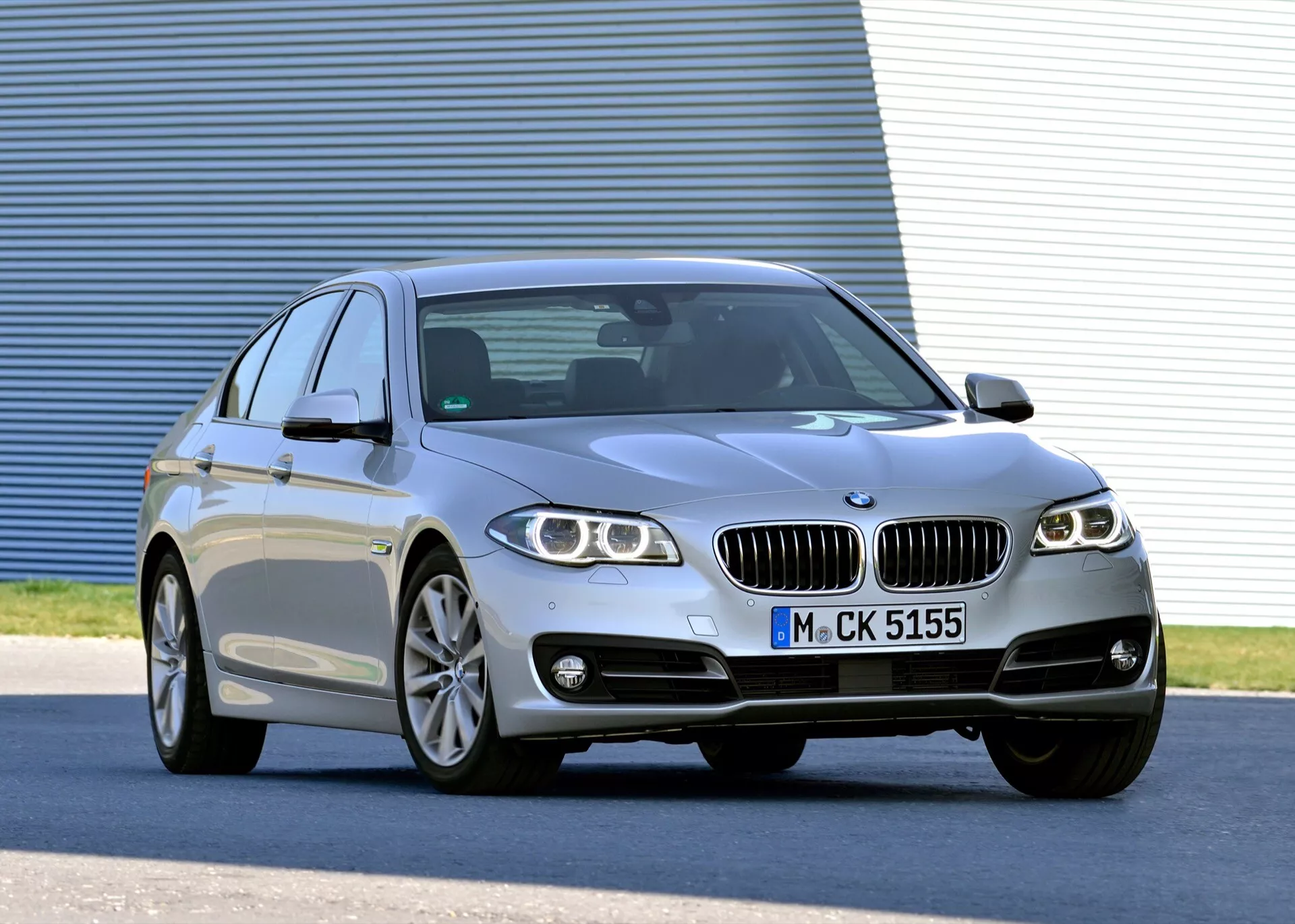 2013-as BMW 5-ös sorozat (F07-F10-F10M-F11-Facelift) ezüst luxus szedán háromnegyedes előlnézetben bemutatva LED fényszórók, ötvözet kerekek, dupla vese alakú hűtőrács, sportos négyajtós karosszéria kupé szerű tetővonallal és fejlett technológiai jellemzőkkel