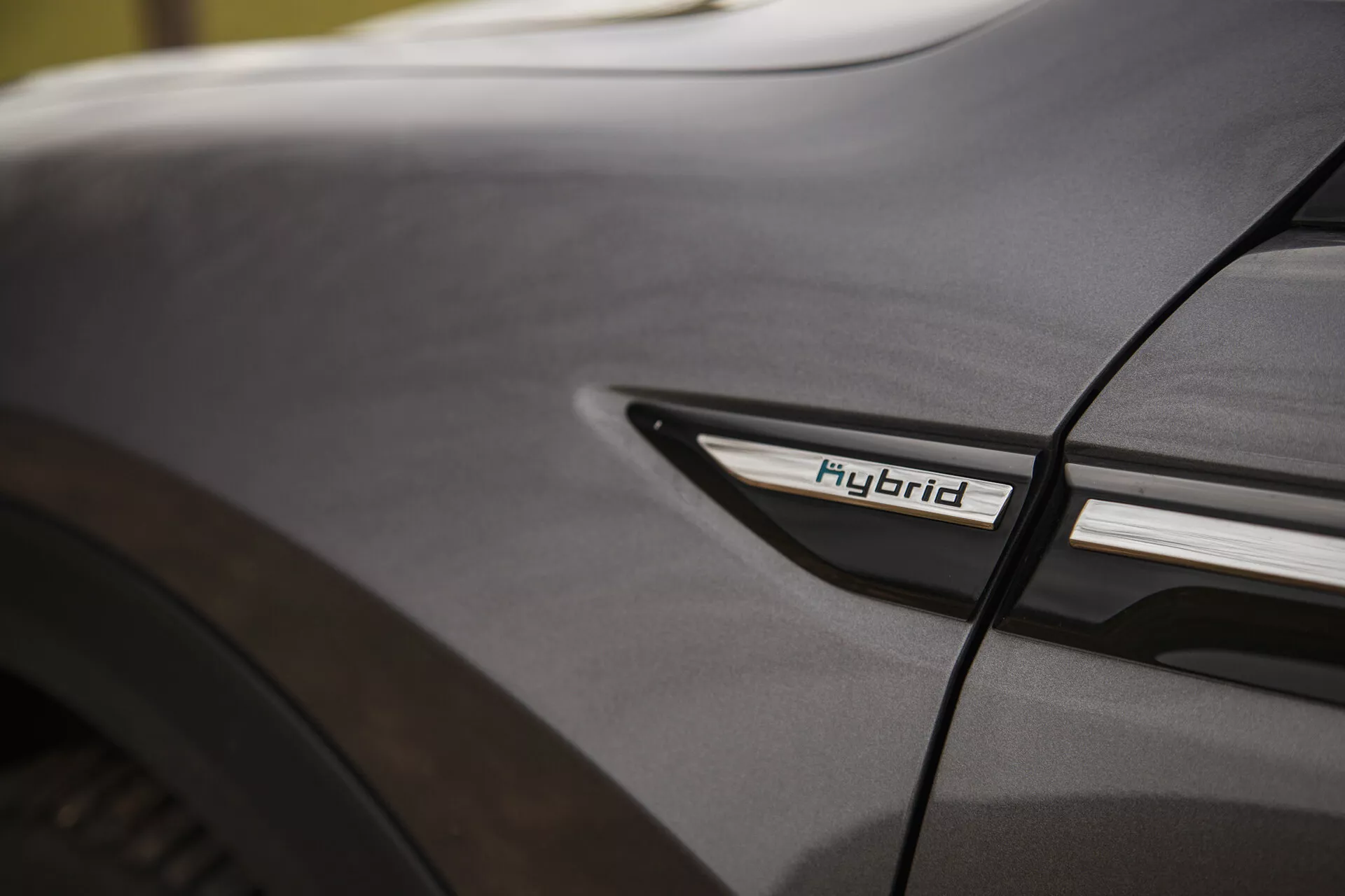 Közeli részlet a Citroen C5-X 2022-ről az Öko jelzéssel az alsó oldalsó profilban a hátsó kerékjáratnál, kiemelve a hibrid technológiát és a design esztétikát lágy világítási körülmények között