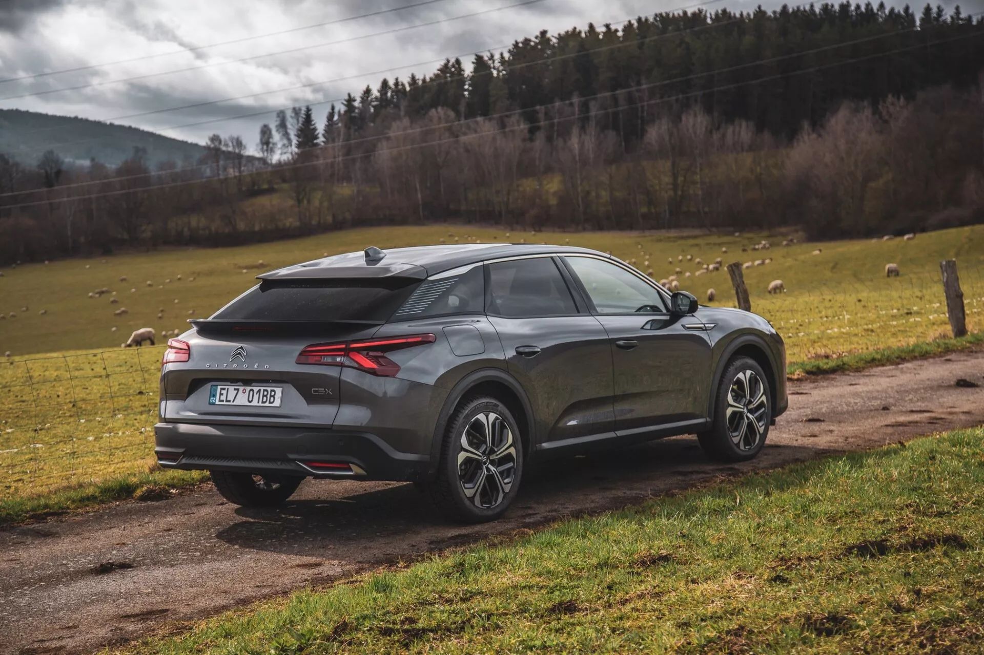 2022-es Citroen C5-X modern crossover SUV parkol a szabadban, hátulról háromnegyedes nézetben kiemelve a LED-es hátsó lámpákat, a hátsó diffúzort, parkolóérzékelőket vagy kamerát, cápauszony-antennát, kéttónusú ötvözött kerekeket, lejtős hátsó ablakot, integrált spoilerrel és fémes befejezéssel, természetes tájkép előtt