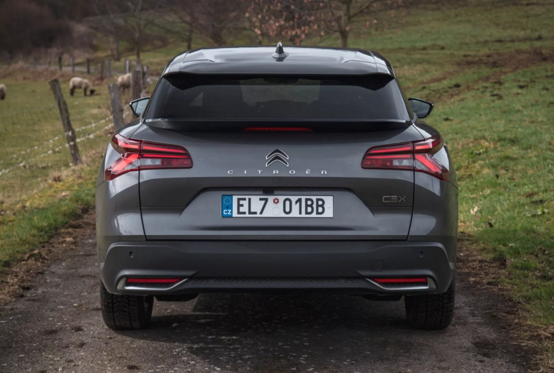 2022-es Citroën C5X hátsó nézete kavicsozott úton természetes háttérrel, bemutatva az LED-es hátsó lámpák, parkolótávolság-ellenőrzés, kettős kipufogó és további külső részletek.