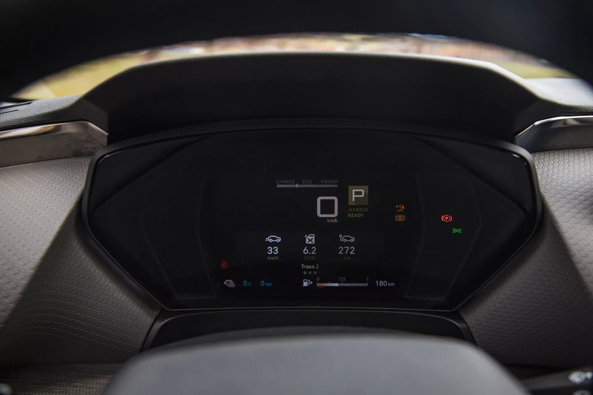 Közeli nézet egy Citroen C5-X 2022 digitális műszerfalára, amely az autó metrikáit jeleníti meg, beleértve a sebességváltó jelzőt, sebességmérőt és energiafogyasztást, elmosódott kormánykereket és szélvédőt az előtérben és háttérben egyaránt.