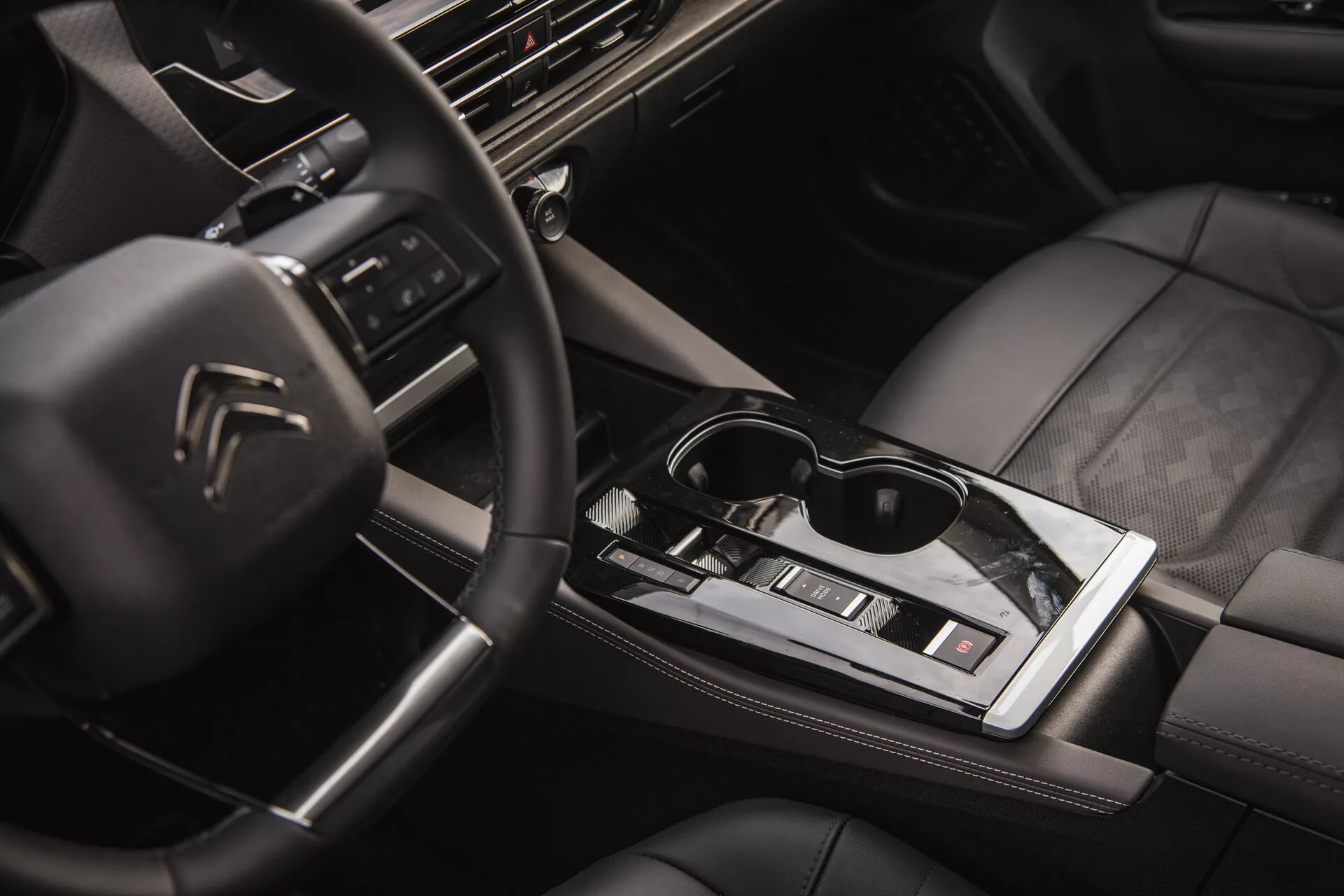 Citroën C5-X 2022 belső nézete, amely bemutatja a multifunkciós kormányt logóval, a high-tech műszerfalat infotainment rendszerrel, az elegáns automatikus váltókar, a klímavezérlés, a minőségi varrással ellátott bőrülések, és az életmódot sugárzó napszemüveg a központi fényes felületen