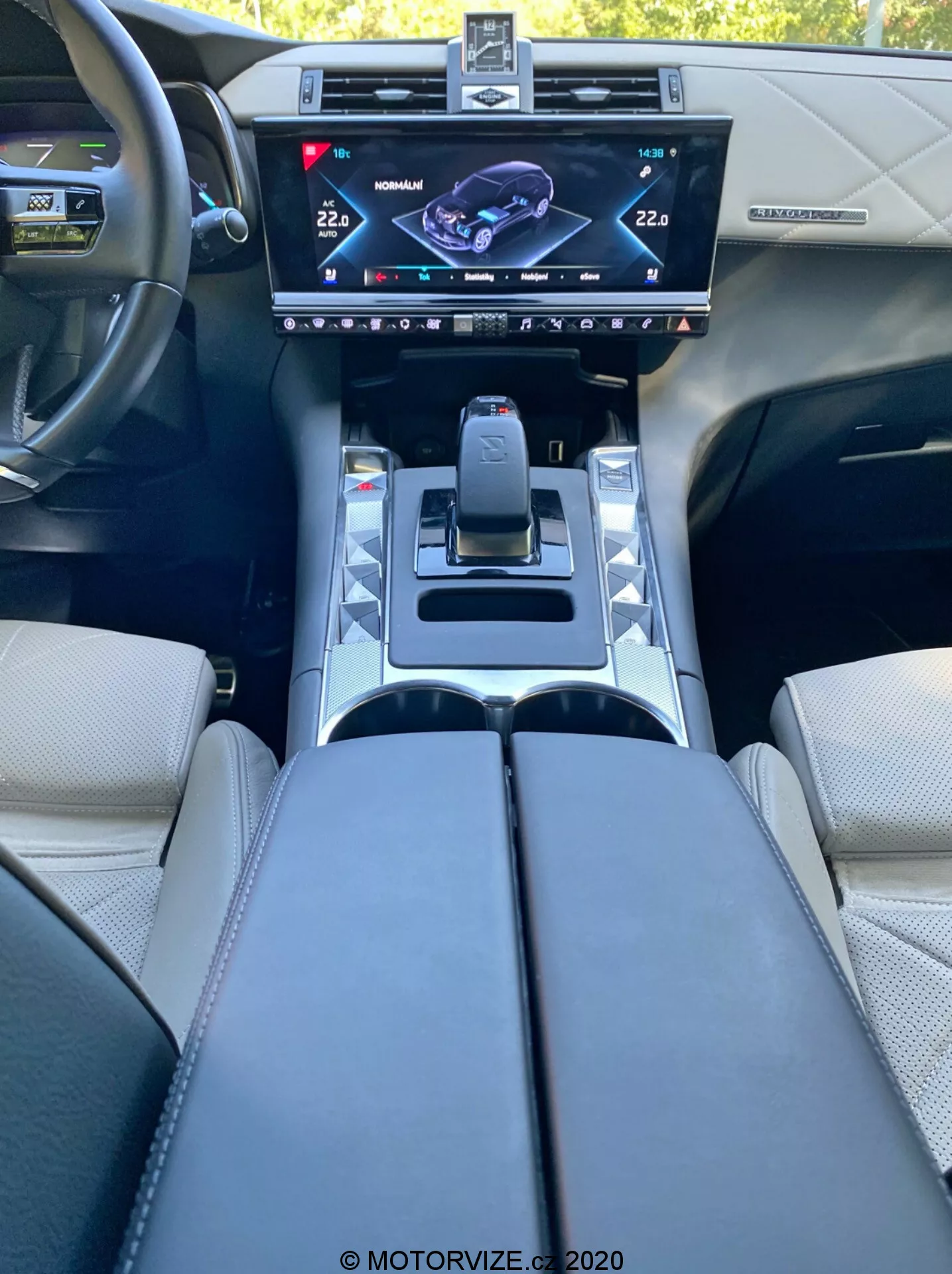 A 2018-as DS Automobiles DS 7 Crossback belső nézete a vezetőülésből, bemutatva a központi konzolt nagy felbontású érintőképernyős infotainment kijelzővel, modern sebességváltóval, vezetési mód gombokkal, pohártartókkal, kárpitozott kartámaszokkal és vezérlőgombokkal ellátott kormánnyal, a korszerű autók tervezését és technológiáját tükrözve.