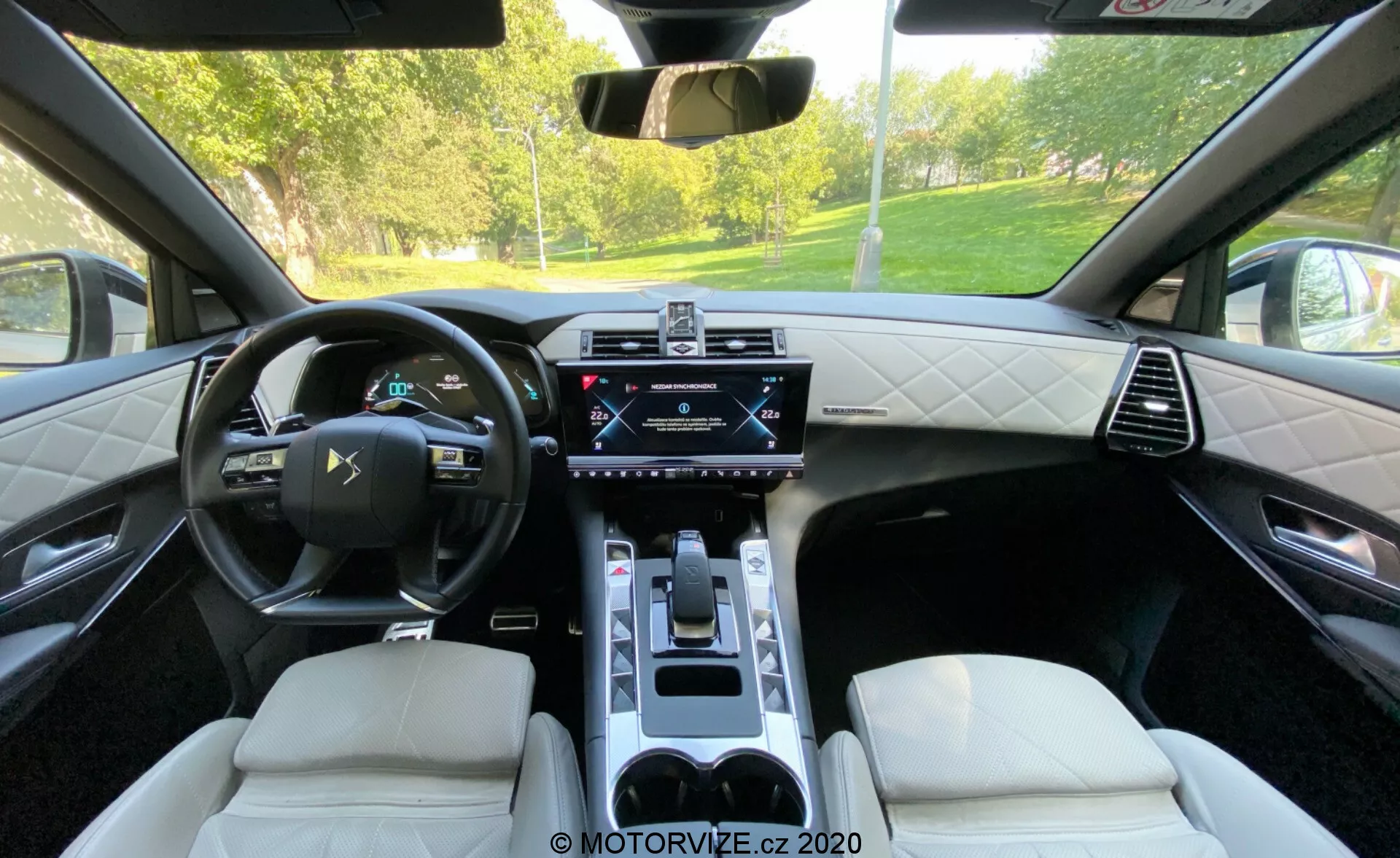 A 2018-as DS Automobiles DS 7 Crossback belső tere a hátsó ülések felől nézve. A képen bőrborítású, multifunkciós kormánykerék, digitális műszeregység, központi érintőképernyős infotainment rendszer, klímavezérlő panel, elektronikus váltókapcsoló, gyémánt varrású bőrülések és pohártartókkal ellátott középkonzol látható. A kép a csúcstechnológia és a kifinomult dizájn kombinációját ábrázolja.