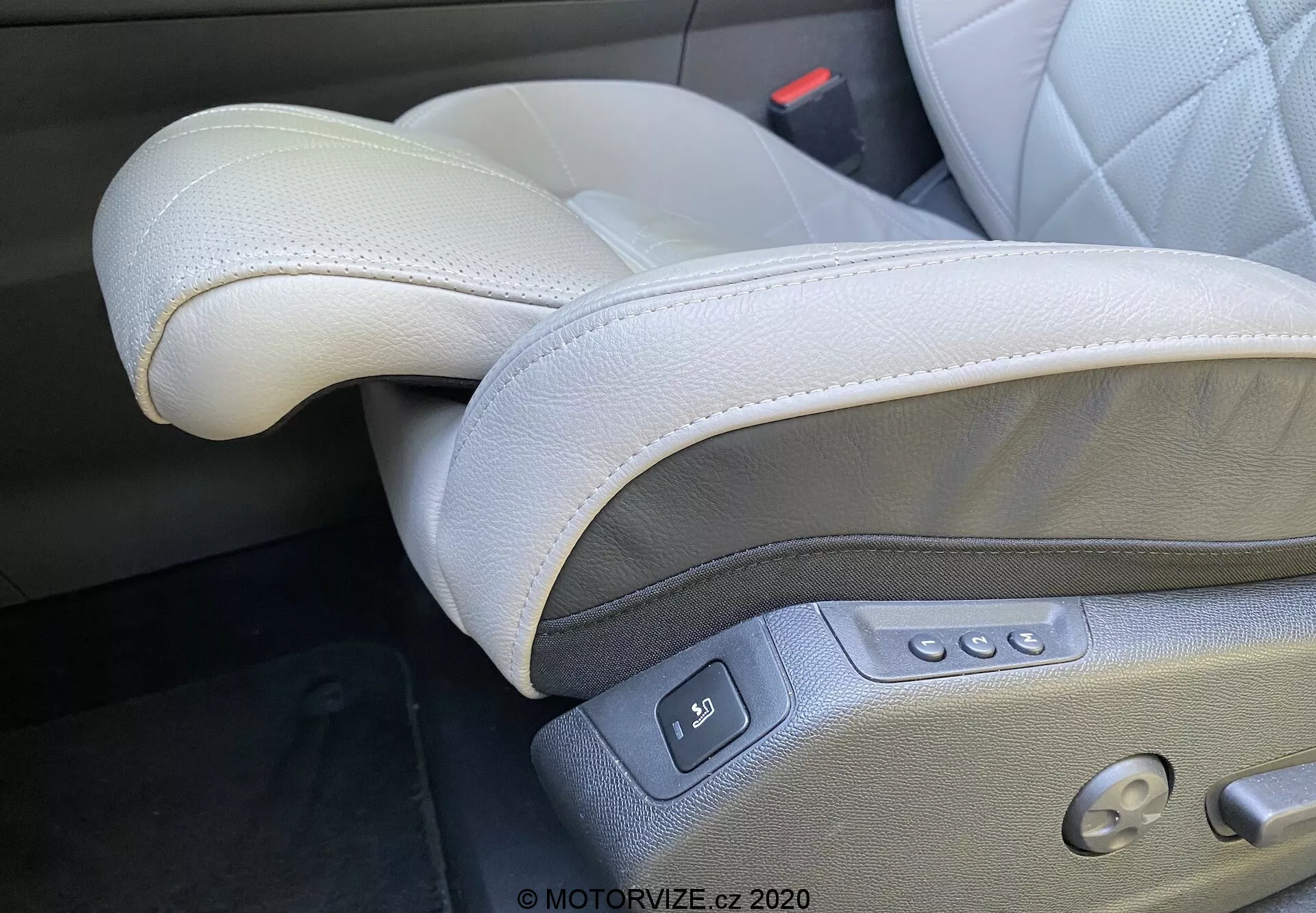 Közelkép a DS Automobiles DS-7 2018 (DS-7 Crossback) belsejéről, amely a bal oldalon elhelyezkedő, világosszürke bőr vezetőülésre összpontosít egy bal oldali kormányzású konfigurációban. A látható jellemzők közé tartozik a kiváló minőségű bőr varrással, az állítható fejtámla, a több gombbal ellátott elektromos ülésszabályozás a csúsztatáshoz, döntéshez, magasságállításhoz és deréktámaszhoz, valamint a memória beállítás gombja és egy látható biztonsági övcsat, amely a prémium és ergonómikus kialakítást hangsúlyozza.