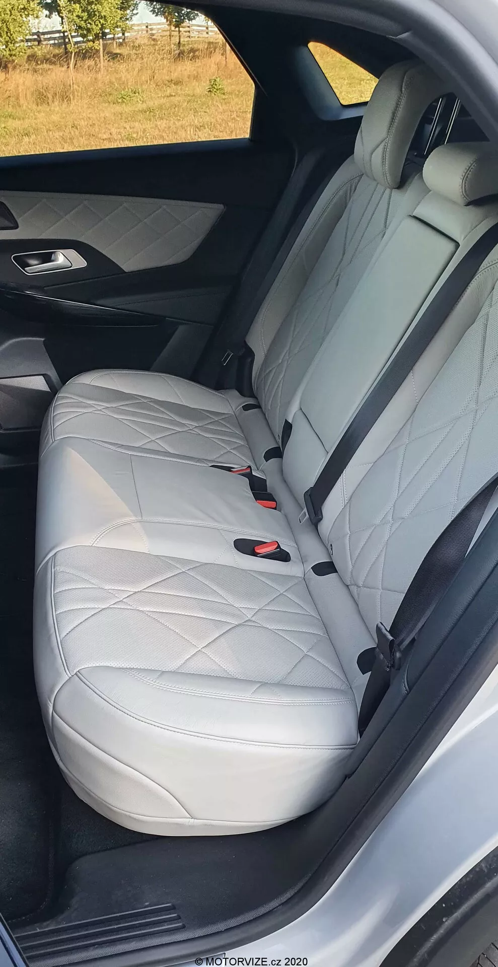 A DS Automobiles DS-7 2018 hátsó utasülésének közeli képe, amely fehér bőrt mutat gyémántvarrással, fejtámlát, hárompontos biztonsági övet és LATCH rendszert, kiemelve az autó luxus belső kialakítását és biztonsági jellemzőit