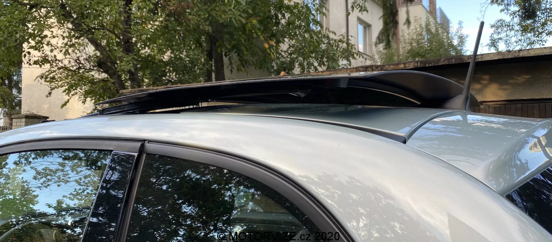 Közelkép egy 2015-ös Fiat 500 tetőszekciójáról, panoráma napfénytetővel, sötétített üveggel és tetősínnel. A kép kiemeli a magas szintű kivitel és hasznos funkciókat, oldalnézetből, a jármű felső részére fókuszálva. Az autó ezüst vagy világosszürke fényezése jó állapotban van, látható karcolások vagy horpadások nélkül.