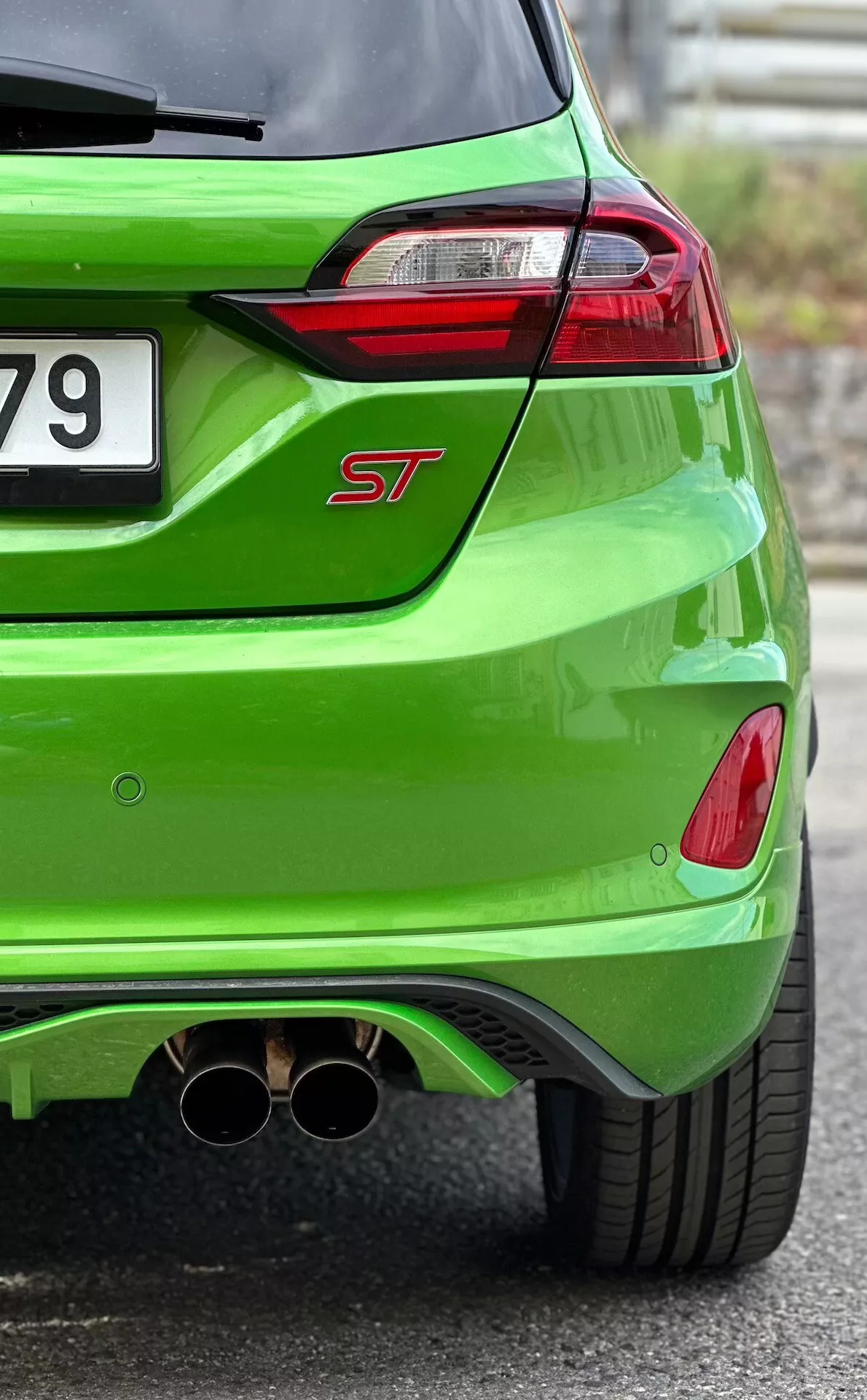 Közeli nézet a 2022-es Ford Fiesta ST hátsó részéről, világoszöld metál befejezéssel, LED-es hátsó lámpákkal, dupla króm kipufogóval és aerodinamikai hátsó differenciálművel
