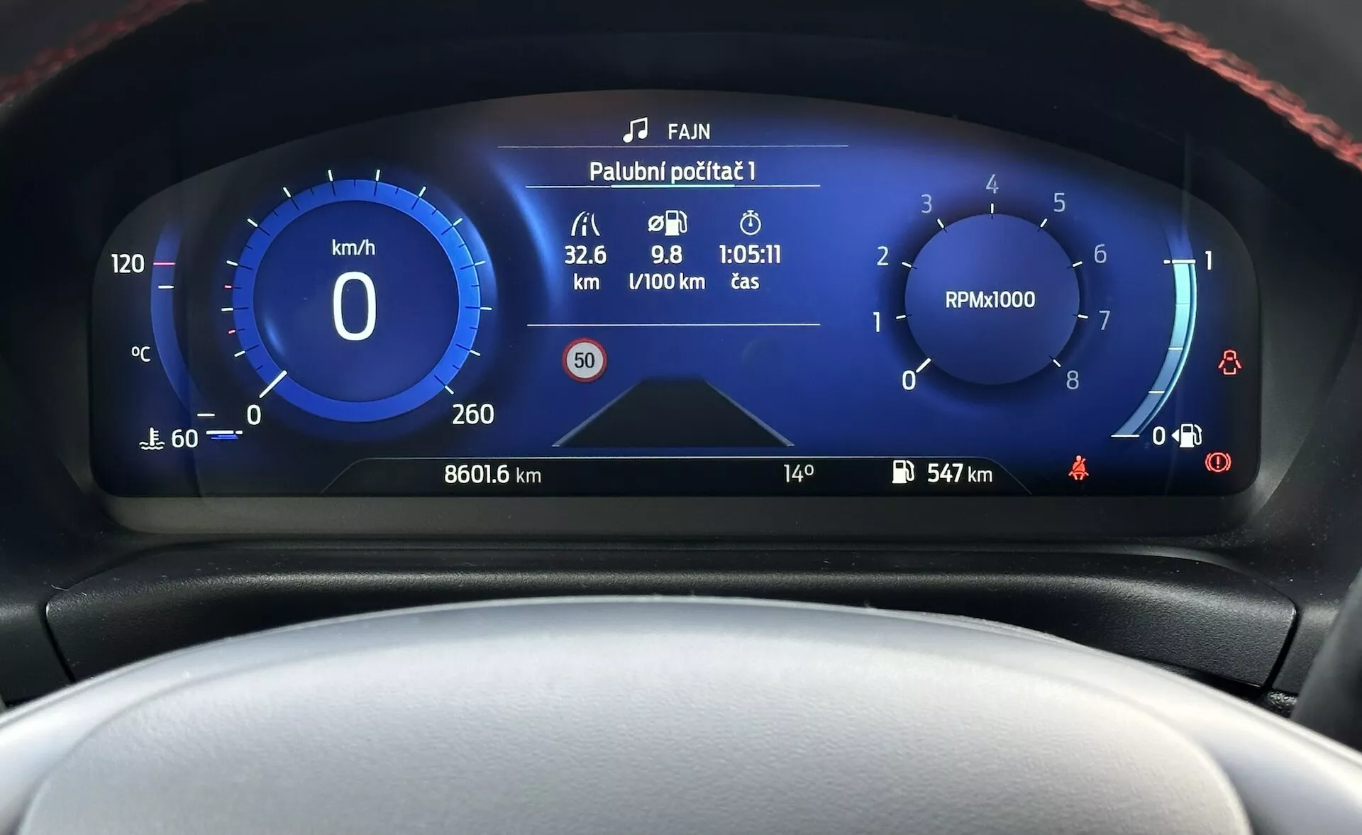 A 2022-es Ford Fiesta digitális műszerfalának közelképe, amely a sebességmérőt, fordulatszámmérőt, üzemanyag-hatékonysági mérőt és különböző járműállapot-jelzőket mutat modern, kék-fehér színösszeállítással.