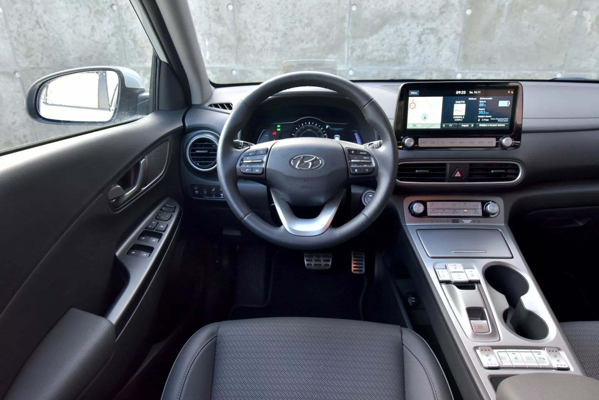 2021-es Hyundai Kona Elektromos autó belső nézete a vezető oldaláról, kormánnyal, műszeregységgel, infotainment érintőképernyővel, klíma vezérlő gombokkal és váltóval