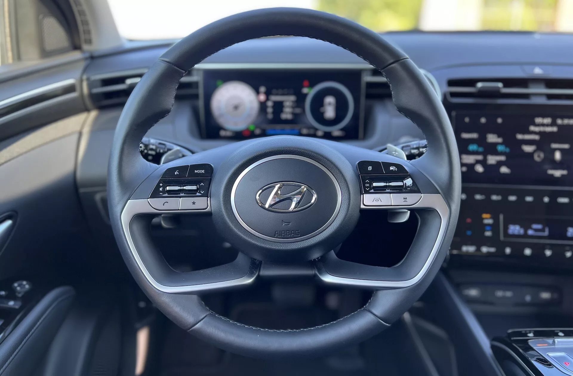 2020-as Hyundai Tucson belső nézete a vezető ülésből, ahol a Hyundai logós kormánykerék, digitális műszerfal és infotainment képernyő látható