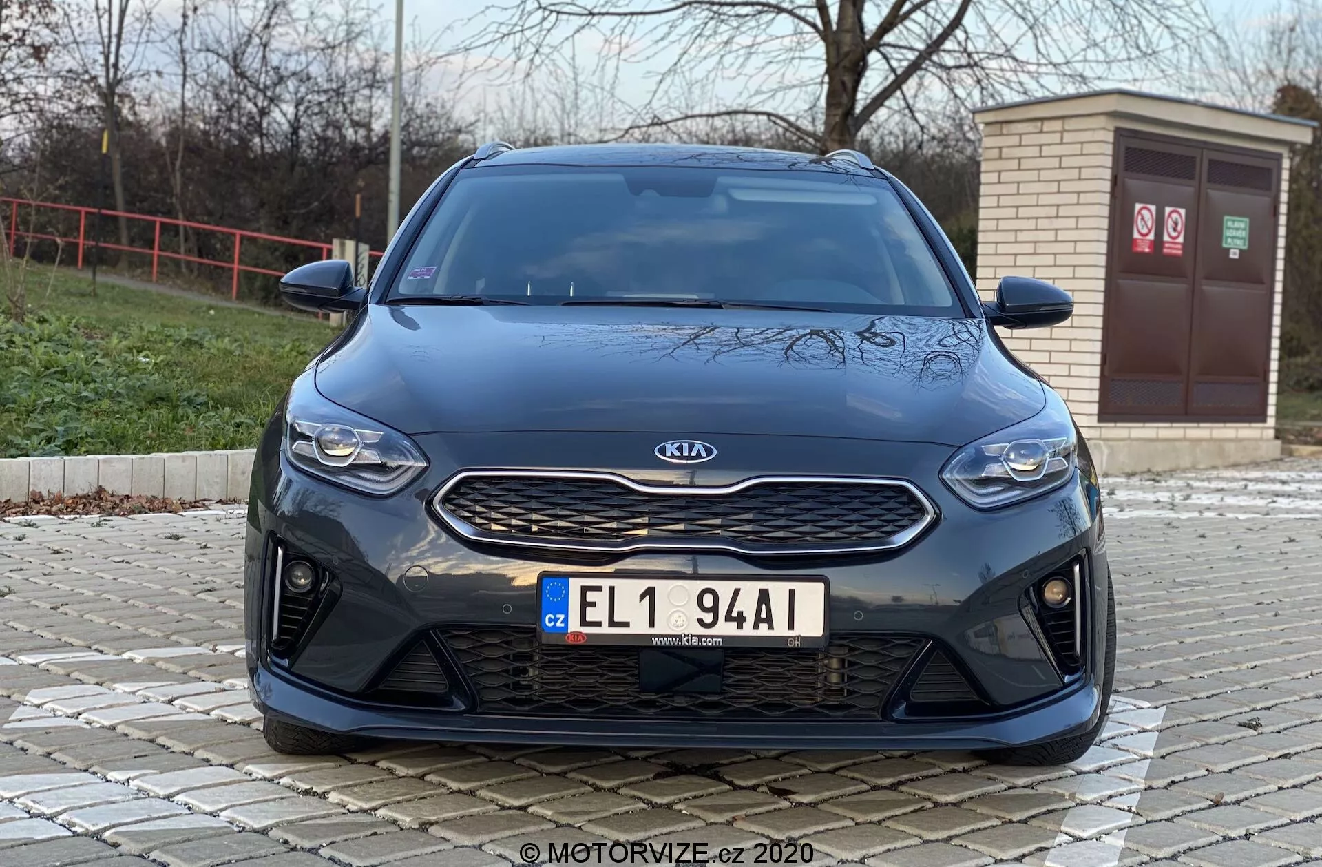 Egy Kia Ceed 2018 elölnézeti képe alacsony szögből, amely bemutatja a modern esztétikájú elülső jellemzőket, mint a hűtőrács, fényszórók és lökhárító. A képen kiemelve látható a texturált fekete hűtőrácson található ezüst Kia jelvény, a karcsú, vízszintes fényszórók és a nagy légbeömlőkkel ellátott első lökhárító, amely sportos teljesítmény jellemzőket vagy fejlett légáramlásos hűtést sugall.