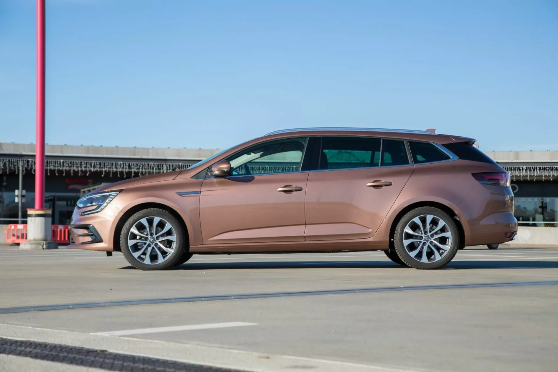 2009-es Kia Ceed kombi metál barack színben, teljes oldalnézet mintás burkolaton, ötvözött kerekekkel és elegáns tervezéssel a tiszta kék ég alatt