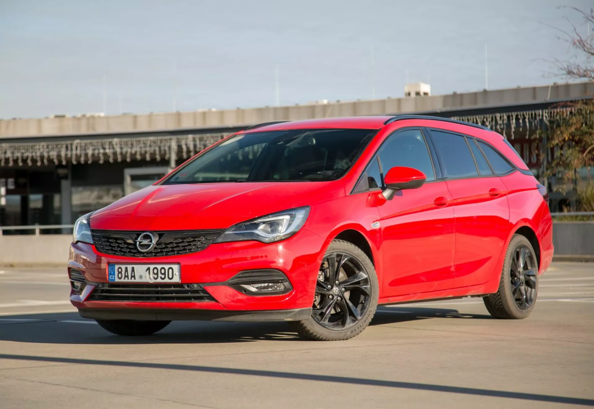 Világospiros 2009-es Kia Ceed hatchback parkol sima betonon tiszta égbolt alatt, nappal mutatva LED fényszórókat, elegáns hűtőrácsot, sötét ötvözetű kerekeket és modern aerodinamikus tervezést háromnegyed elölnézetből.