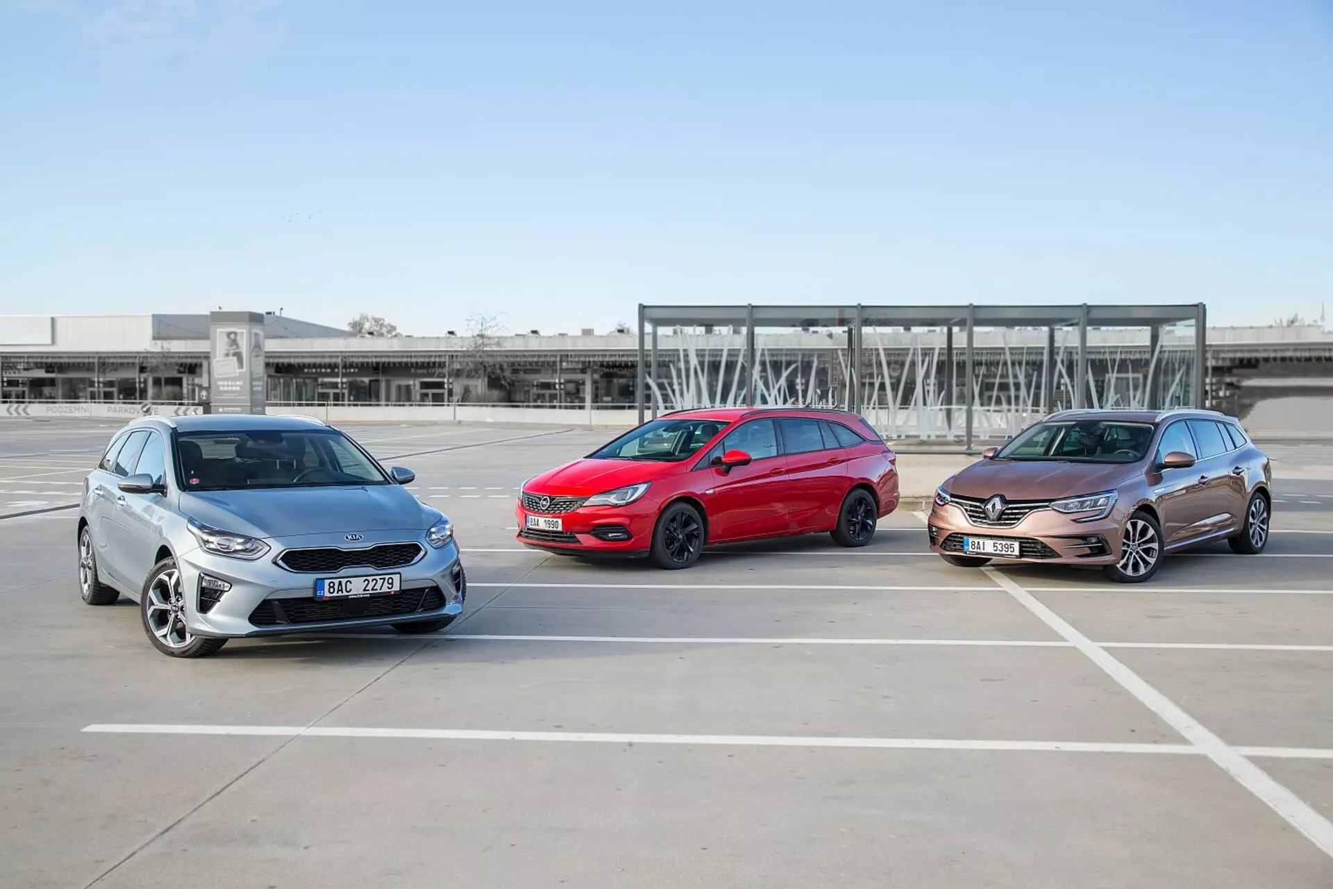 Három Kia Ceed 2009 modell, lépcsőzetesen elrendezve egy üres parkolóban, bemutatva azokat az első- és oldalnézeteket tiszta időjárási körülmények között