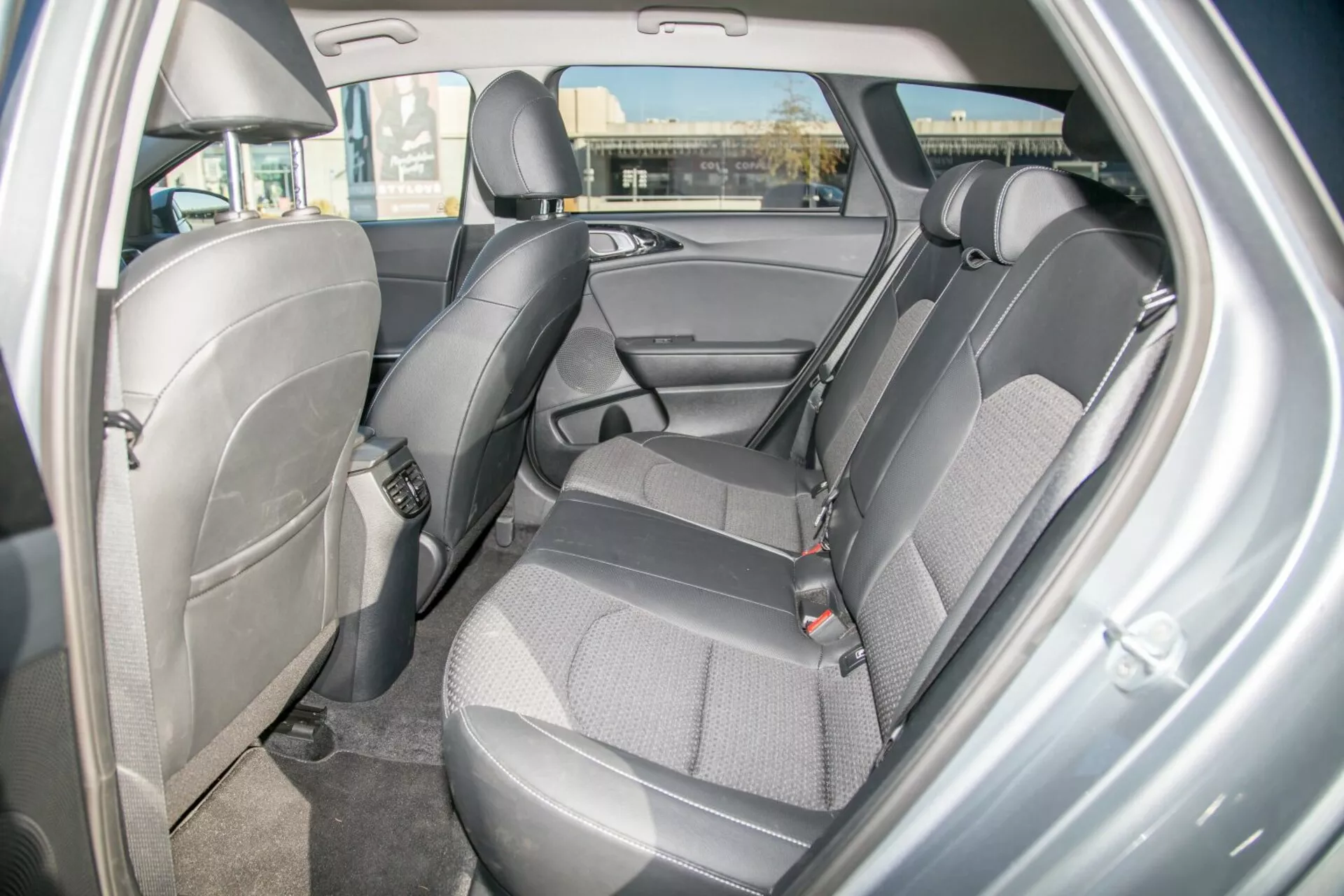 2009-es Kia Cee'd belső terének nézete, amely bemutatja a hátsó ülés területének tervezését és jellemzőit, kiemelve a tartós kéttónusú szövetkárpitozást, látható biztonsági öveket, állítható fejtámlákat, ajtópanelt tárolórekesszel, lehetséges gyermekülés rögzítési pontokat, szőnyegezett padlót és az ambientális kupola világítást a jobb oldali hátsó utasajtó nézőpontjából.