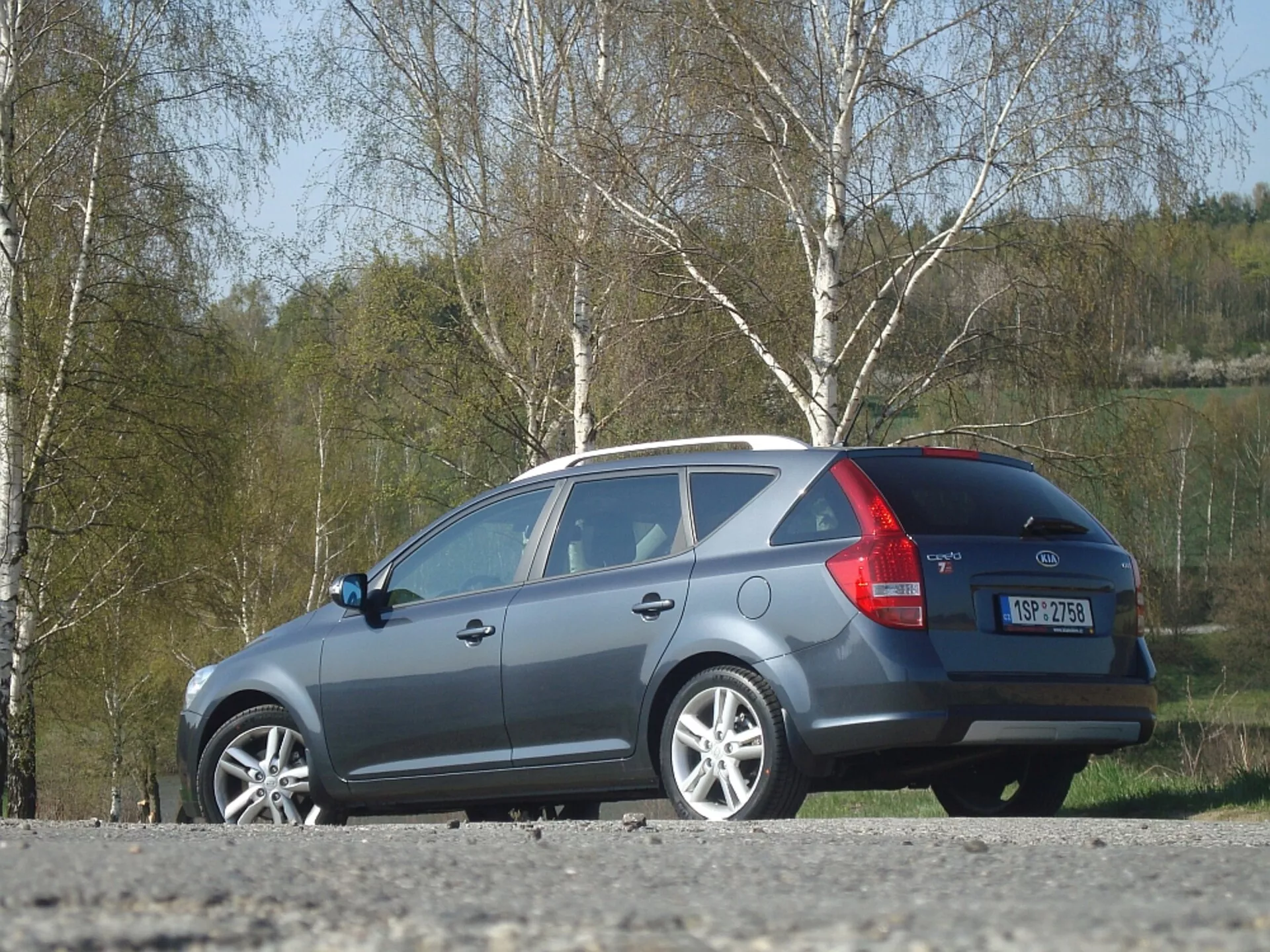 2009-es szürke Kia Ceed kombi, amely az oldalát és hátulját mutatja, hangsúlyozva az aerodinamikus tetővonalat, hátsó lámpákat és hátsó ablakot, kültéri parkolásban