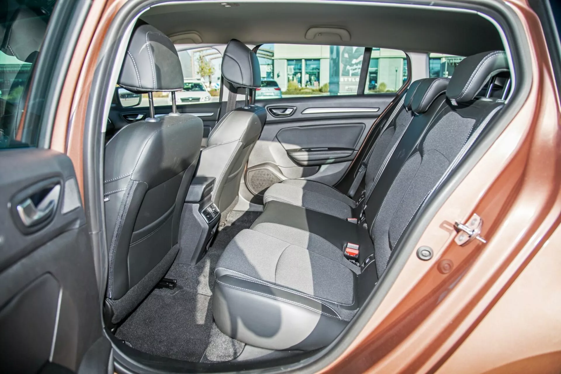 2009-es Kia Ceed belső terének bemutatása, amelyben a kétszínű hátsó pad ülés látható, az egyik ülés előre hajtva a csomagtér számára, biztonsági övek, fejtámlák, elektromos ablakvezérlők és ajtóhangszóró, kiemelve a rugalmas üléskonfigurációt és a luxus kialakítást