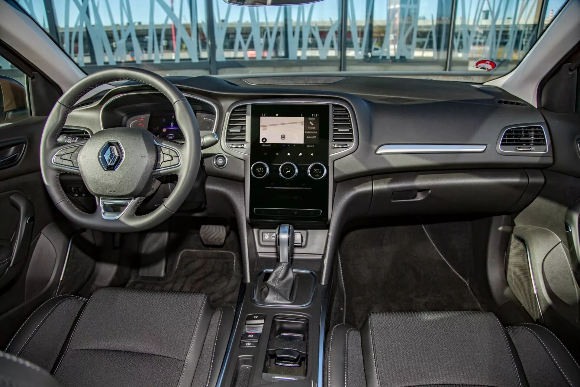 Kia Cee'd 2009 belső nézete a hátsó ülésből, megjelenítve a multifunkciós kormányt, érintőképernyős infotainment rendszert, automata váltót és részletes kárpitozást az első kokpit területén