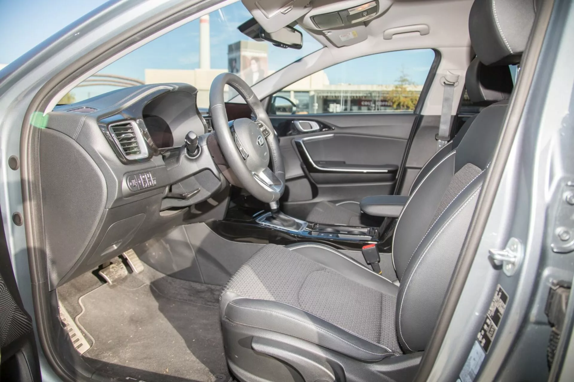 2009-es Kia Cee'd belső nézete a vezető oldaláról, bemutatva az ülést, az integrált vezérlőkkel ellátott kormánykereket és a műszerfal jellemzőit, beleértve a multimédiás rendszert