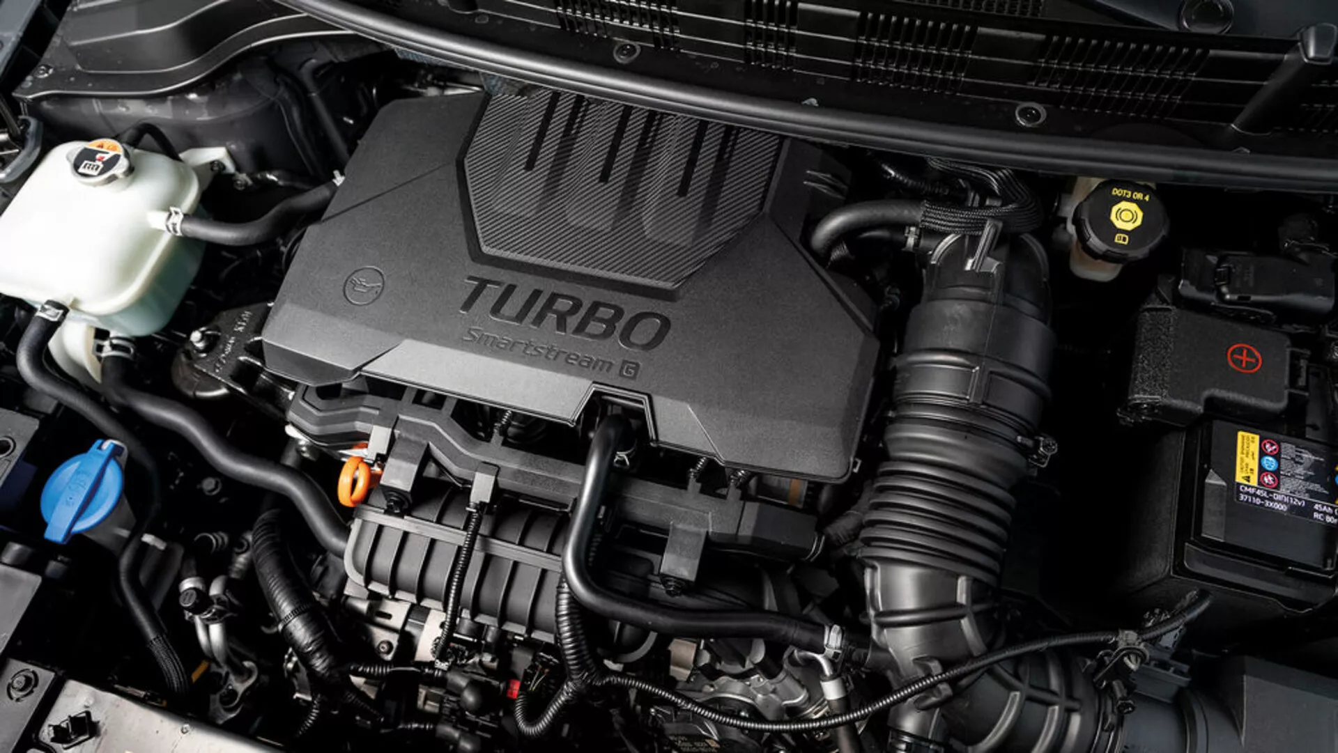 Közeli nézet a Kia Stonic 2017-es modell motorházára turbofeltöltős motorfedéllel és különböző látható mechanikai alkatrészekkel, amely bemutatja a jármű technológiai aspektusait