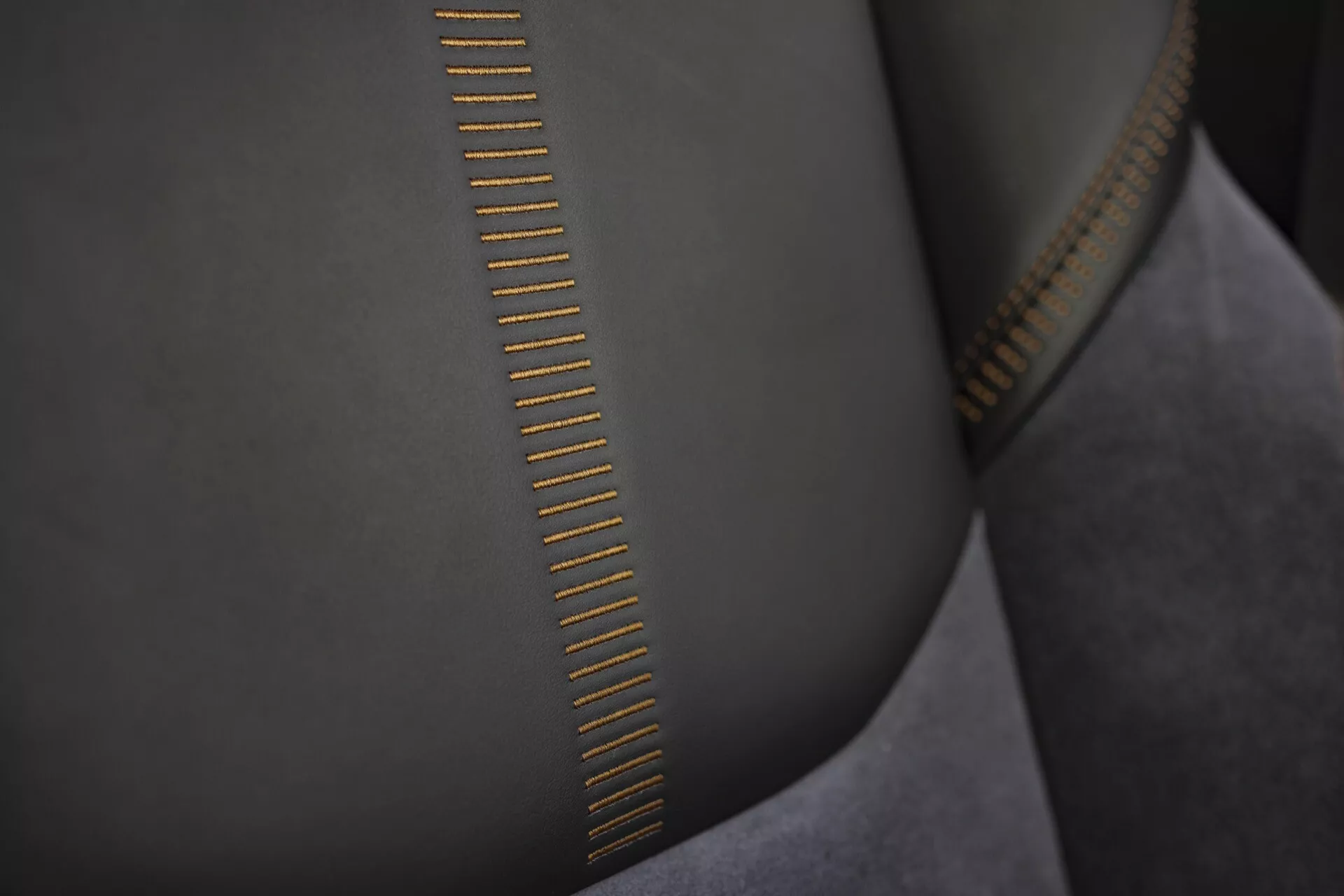 Magas minőségű cipzár fogainak részletes nézete, részletes varrással a sima, velúrszerű anyagon és a fényt visszaverő aranyszínű fémes befejezéssel