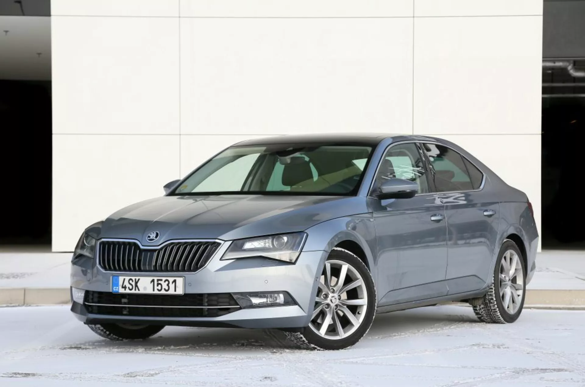 2013-as Mazda 6 szedán háromnegyed előlnézetben, kiemelve a tervezést, az első hűtőrácsot, az éles LED fényszórókat és a stílusos ötvözet kerekeket, havas talajon parkolva városi háttérrel