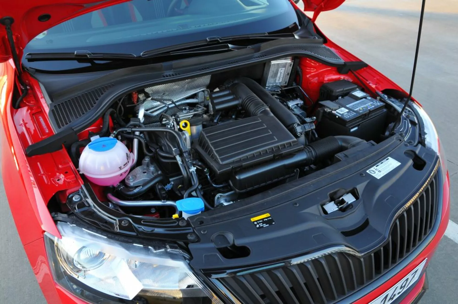 Közelkép egy 2005-ös Opel Astra (Astra TwinTop) nyitott motorháztetőjéről, amely kiemeli a mechanikai komponenseket, mint a légszívó doboz, motorfedél, hűtőfolyadék és fékfolyadék tartályok, és az akkumulátor egy előlről nézett, kissé emelt szemszögből