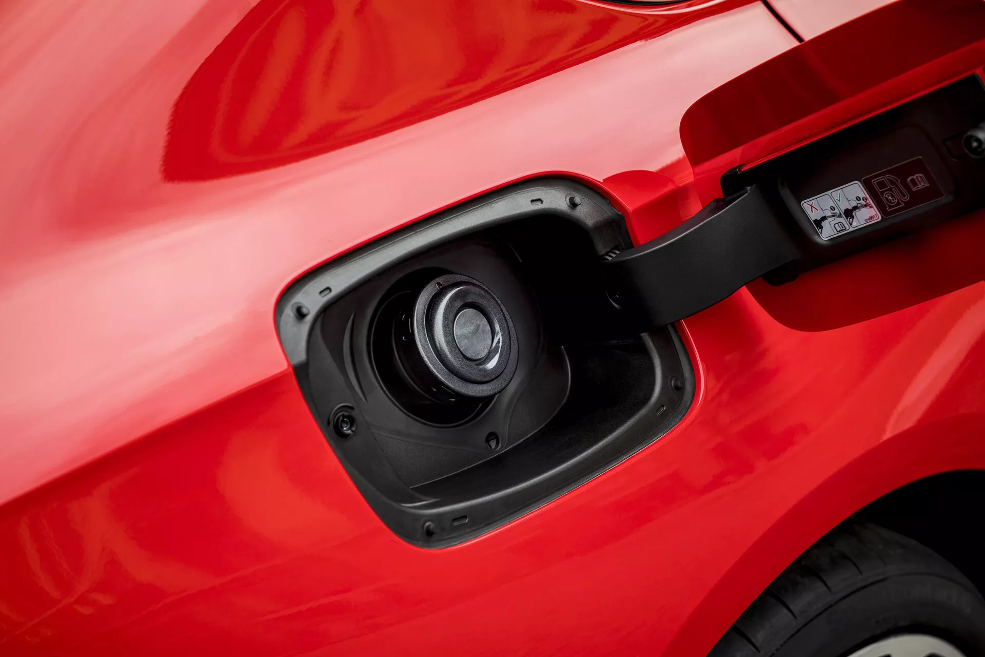 Közeli kép az Opel Insignia 2013 töltőportjáról, amely bemutatja elektromos vagy hibrid képességét részletes kilátással a nyitott töltőport ajtajára és aljzatra a jármű vörös karosszériája ellen