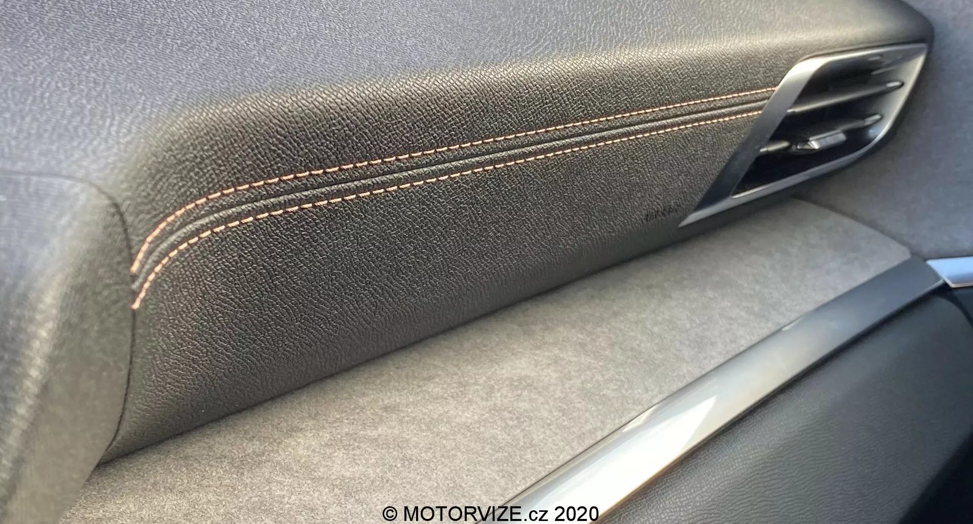 Közeli belső felvétel a 2021-es Peugeot 3008 ajtópanelek belsejéről, kiemelve a bőr textúrájú kartámasz varrott szegélyét és a fém ajtókilincset. Az ezüst díszítőelemek a kézművességre és az anyagminőségre utalnak, árnyékokkal, amelyek a belső fényforrást jelzik.