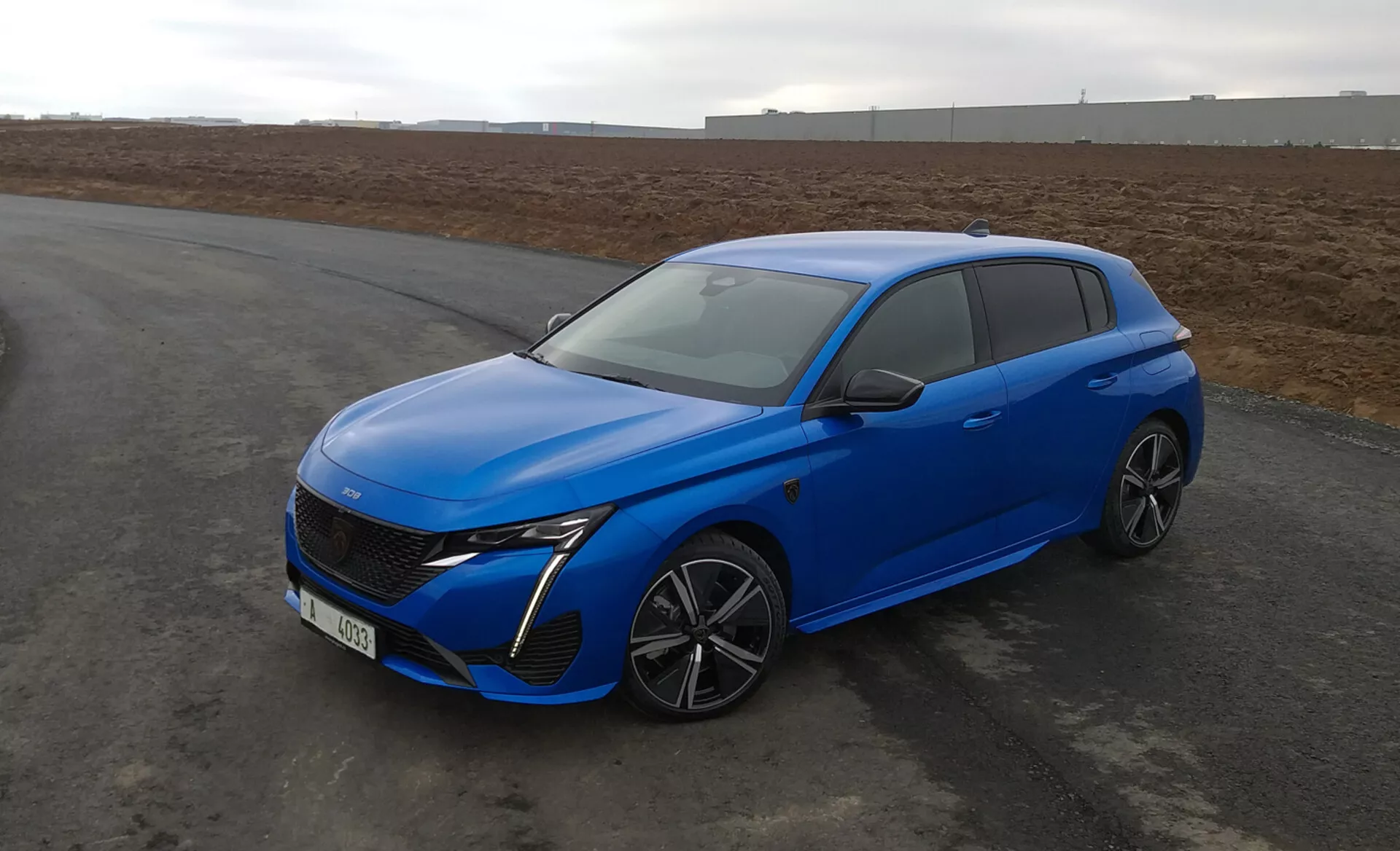 2022-es Peugeot 308 hatchback világoskék színben, aerodinamikus designnal, LED fényszórókkal, fejlett első ráccsal, többsugárzós ötvözött keréktárcsákkal és modern biztonsági jellemzőkkel, aszfalton parkolva