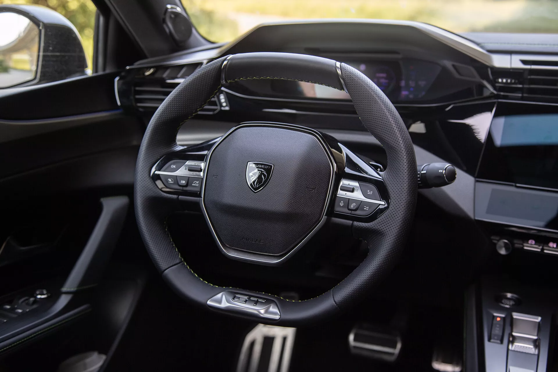 2023-as Peugeot 408 belső terét bemutató modern multifunkcionális kormánykerék márkajelzéssel, digitális műszerfal a háttérben és részben látható középkonzollal infotainment rendszerrel