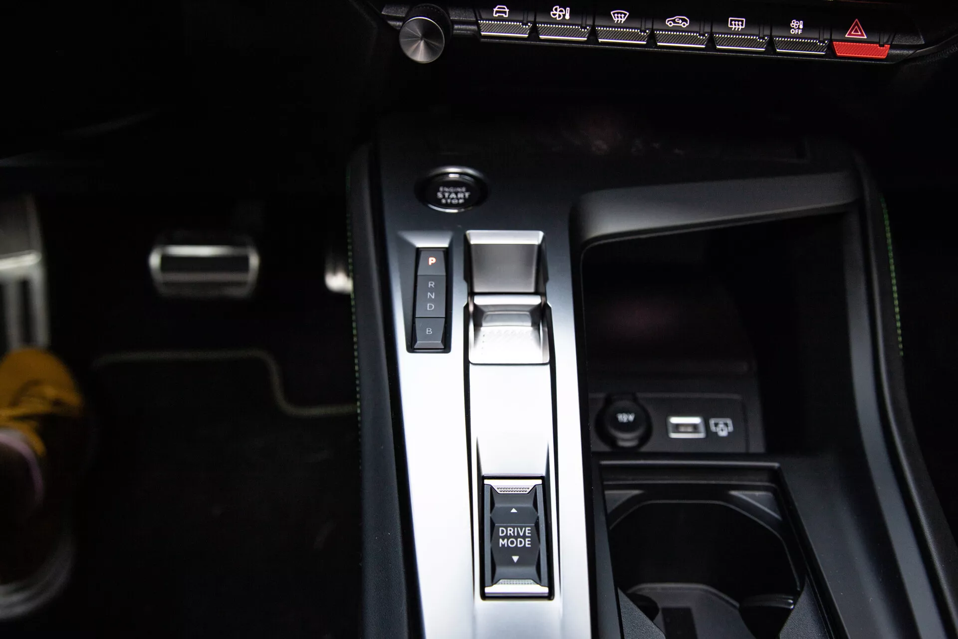 Közeli nézet a Peugeot 408 2023-as modell középkonzoljára, parkoló pozícióban lévő váltókar, DRIVE MODE gomb, elektronikus kézifék és USB portokkal, bemutatva a modern belső kialakítást.