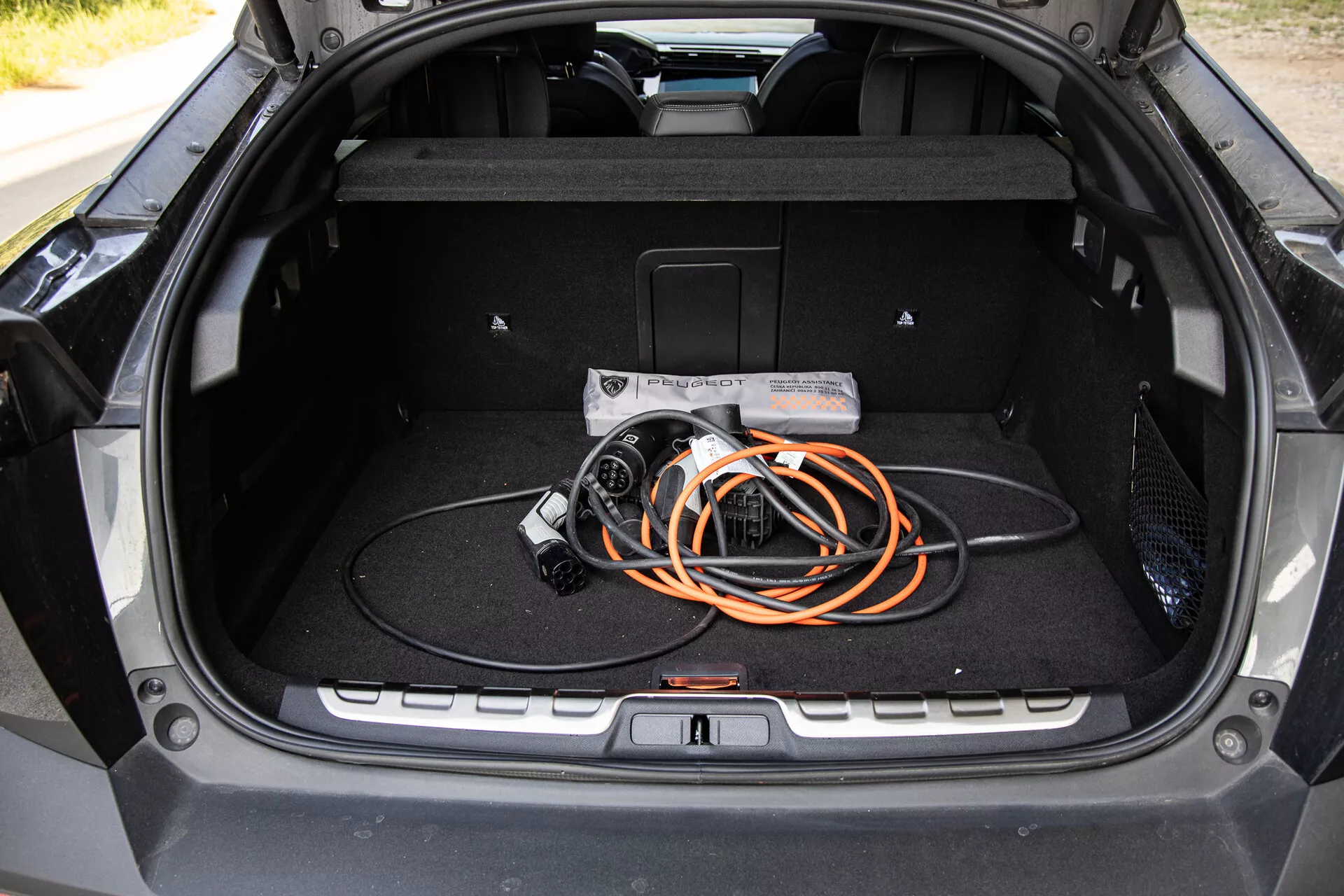 A 2023-as Peugeot 408 csomagtartójának belső nézete, amely tágas tervezést és elektromos jármű töltőkábelt mutat be, kiemelve az EV technológiát és a modern gyártási minőséget.