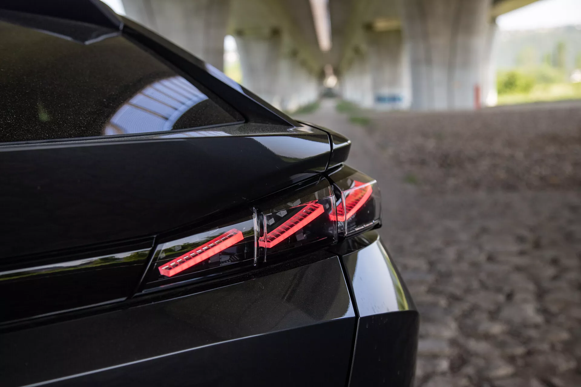 Közelkép a 2023-as Peugeot 408 hátuljáról, bemutatva a LED hátsó lámpát, a karcsú csomagtartó tervezést beépített spoilerrel, és a fényes fekete befejezést strukturált árnyék alatt