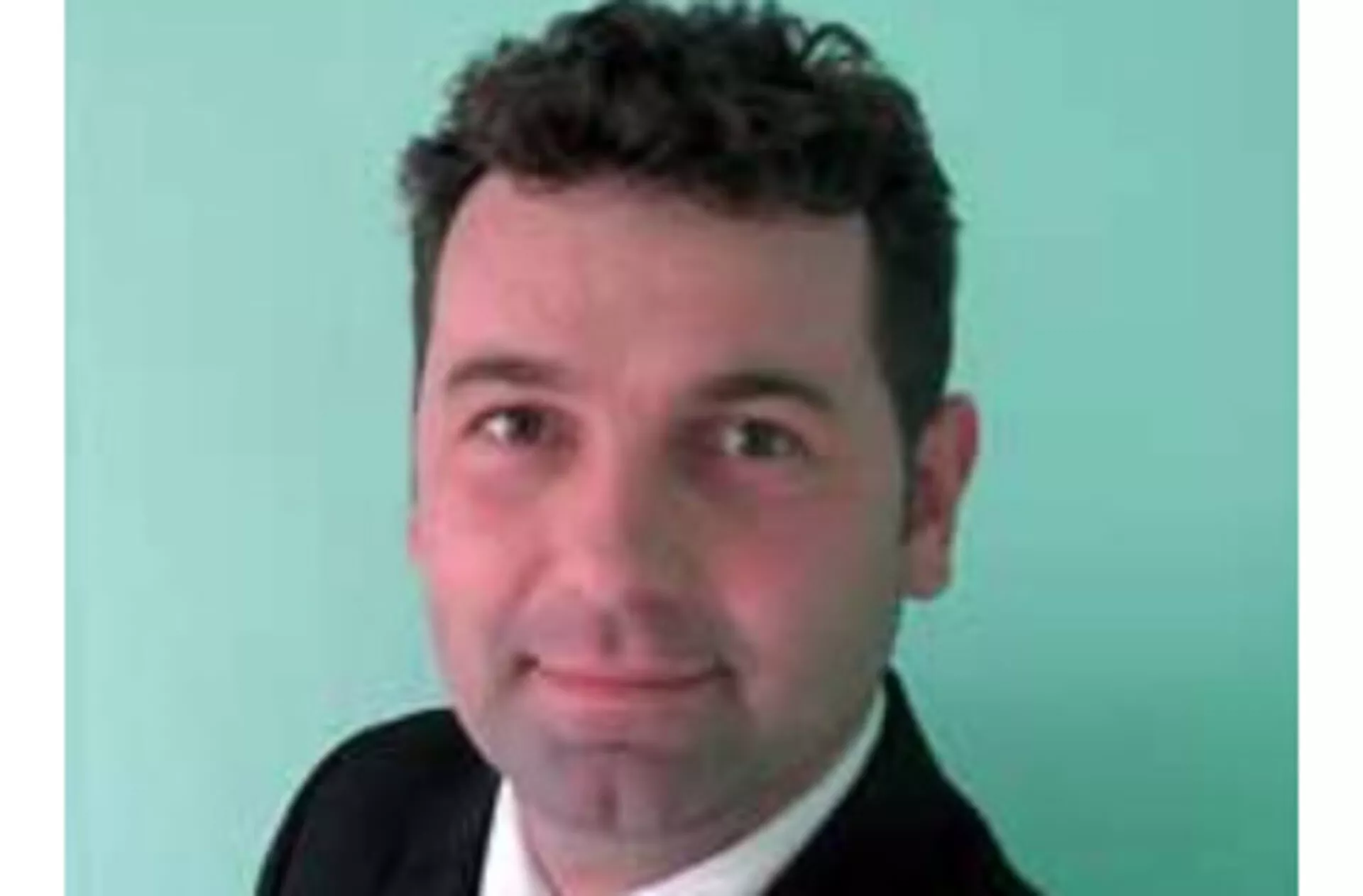 Professzionális fénykép egy rövid sötét hajú férfiról öltönyben világos háttér előtt